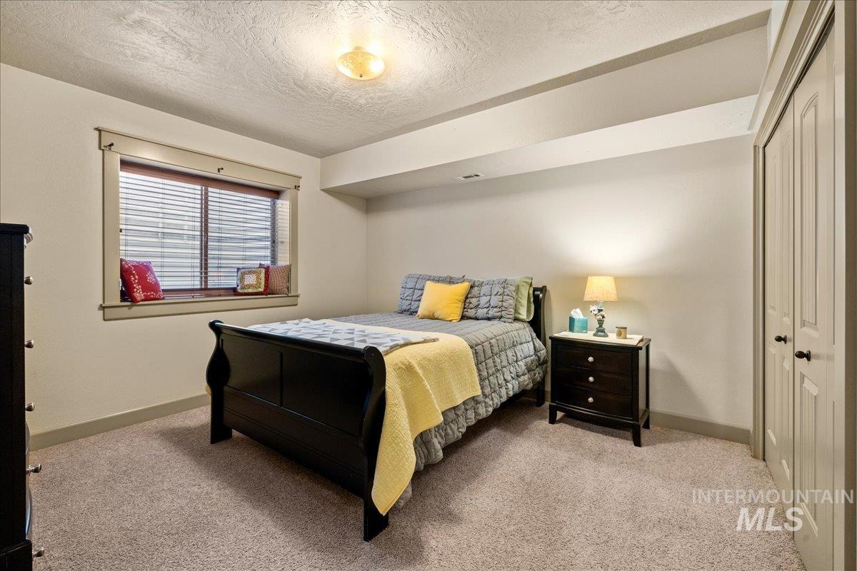 Bedroom featuring light colored carpet, a textured ceiling, and a closet