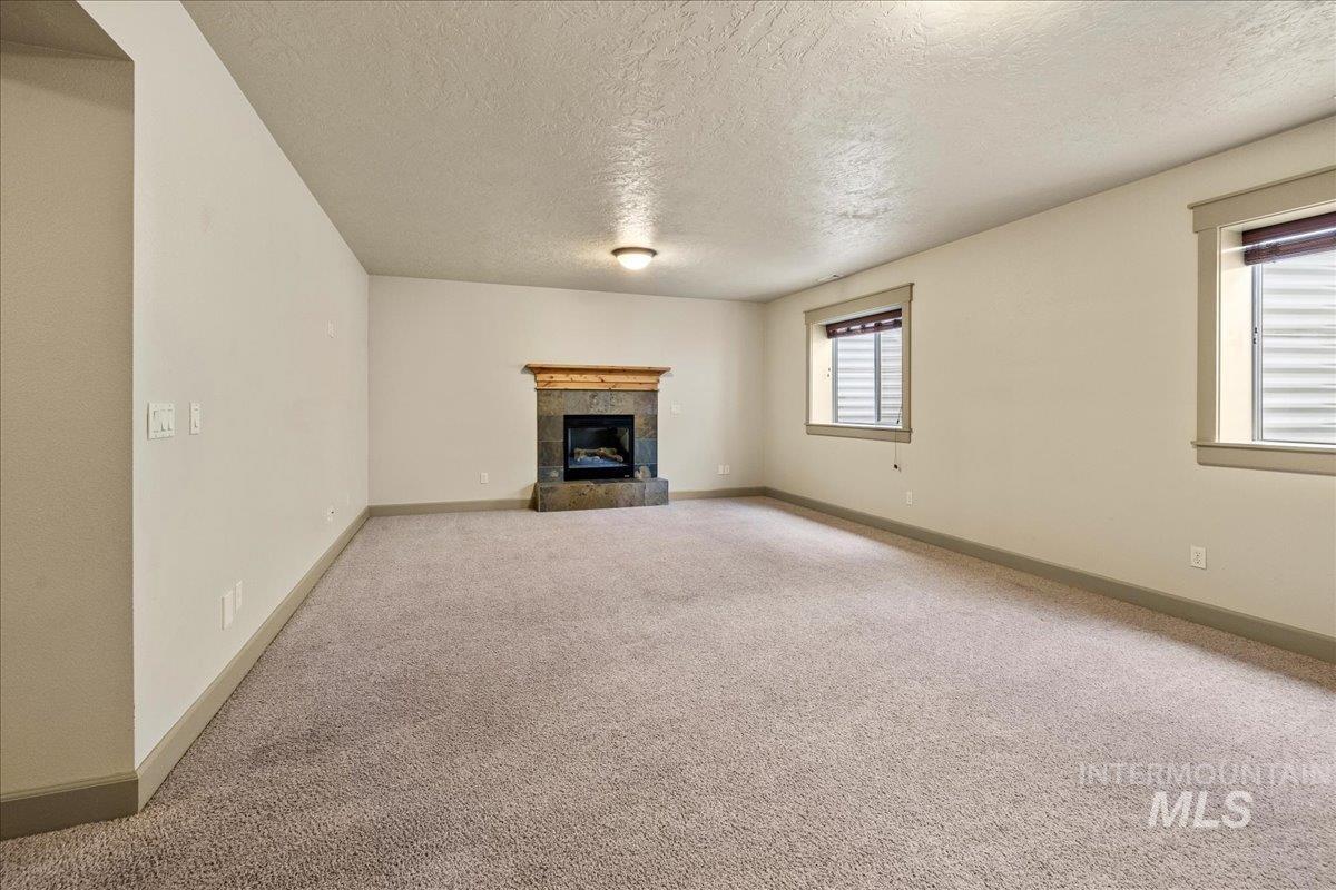 Unfurnished living room featuring a textured ceiling, carpet, and a fireplace