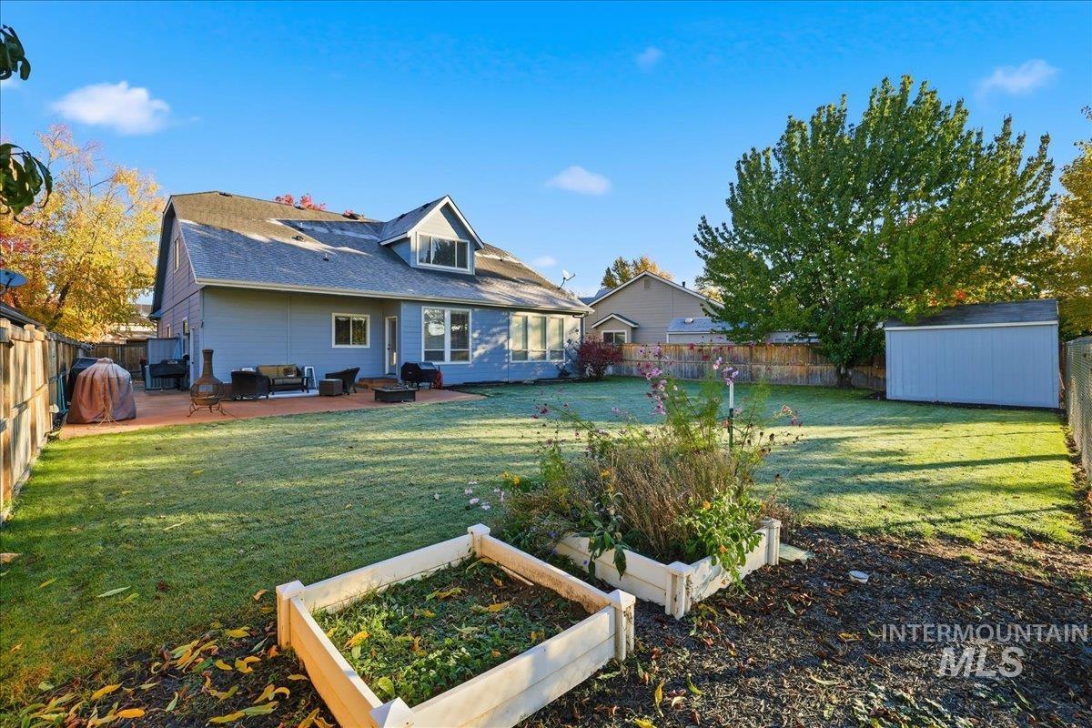 Rear view of house featuring a garden, a fenced backyard, a storage shed, and a patio