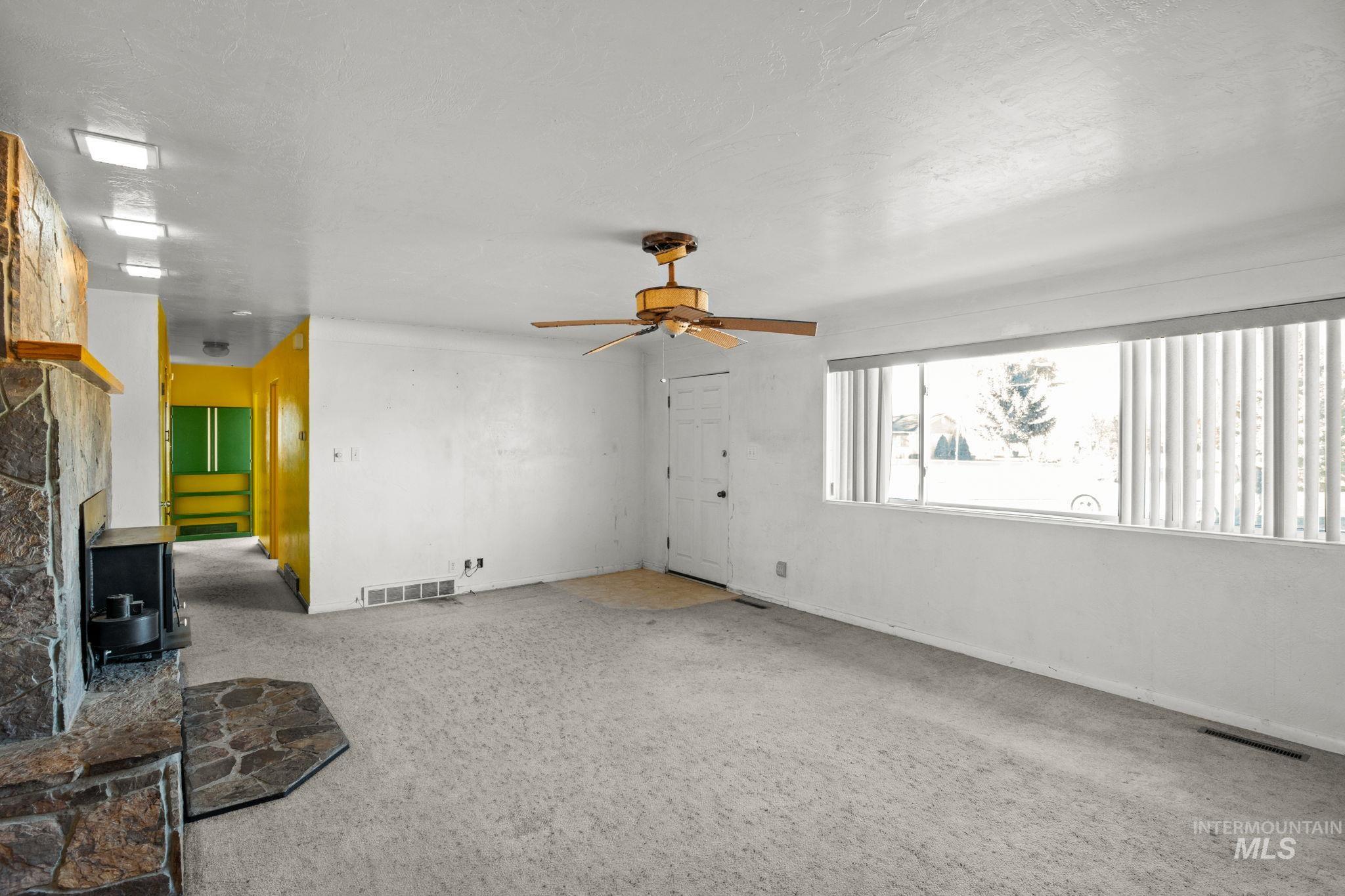 Unfurnished living room featuring carpet and ceiling fan
