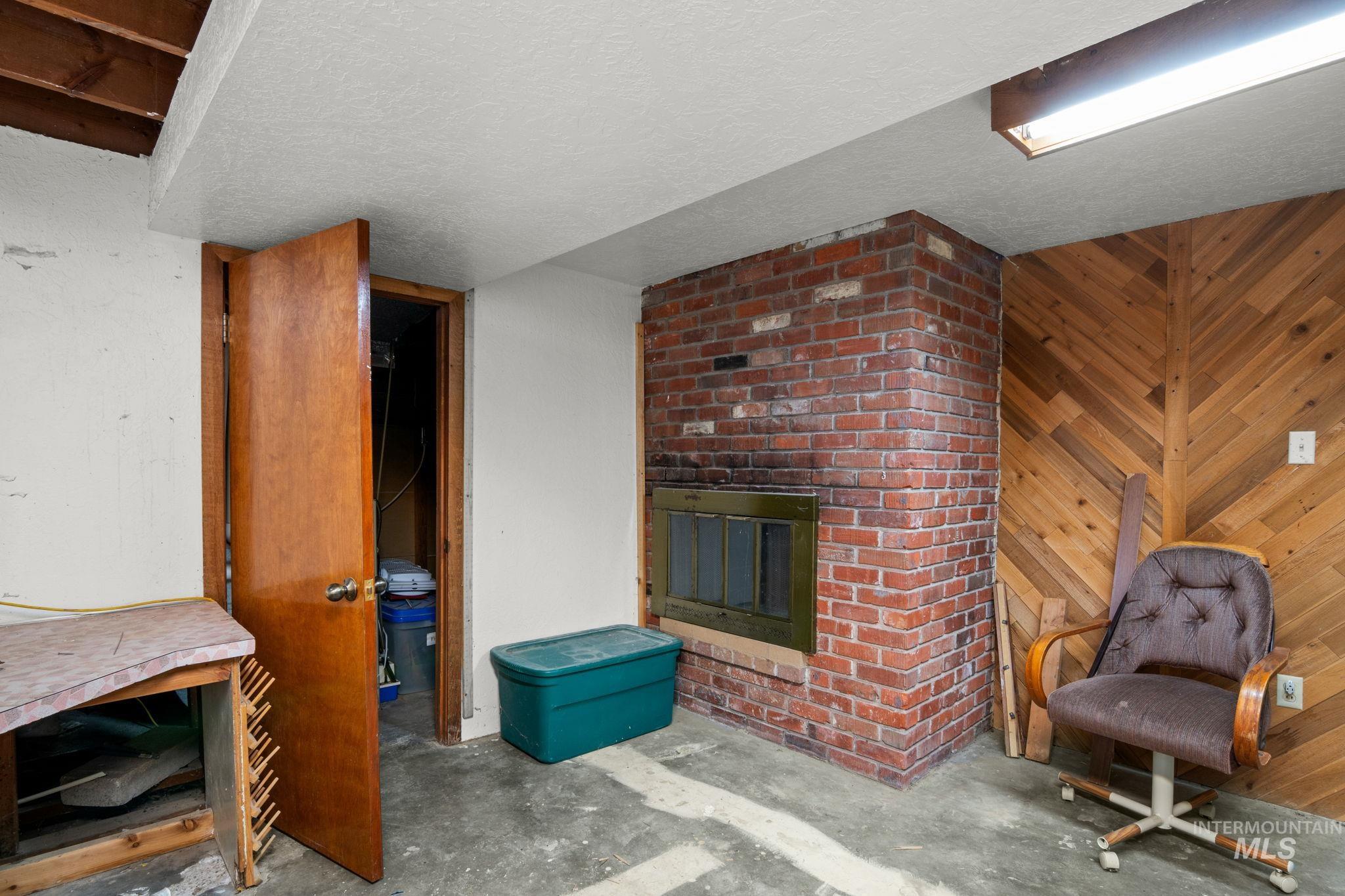 Living room with wooden walls, concrete flooring, a fireplace, and a textured ceiling