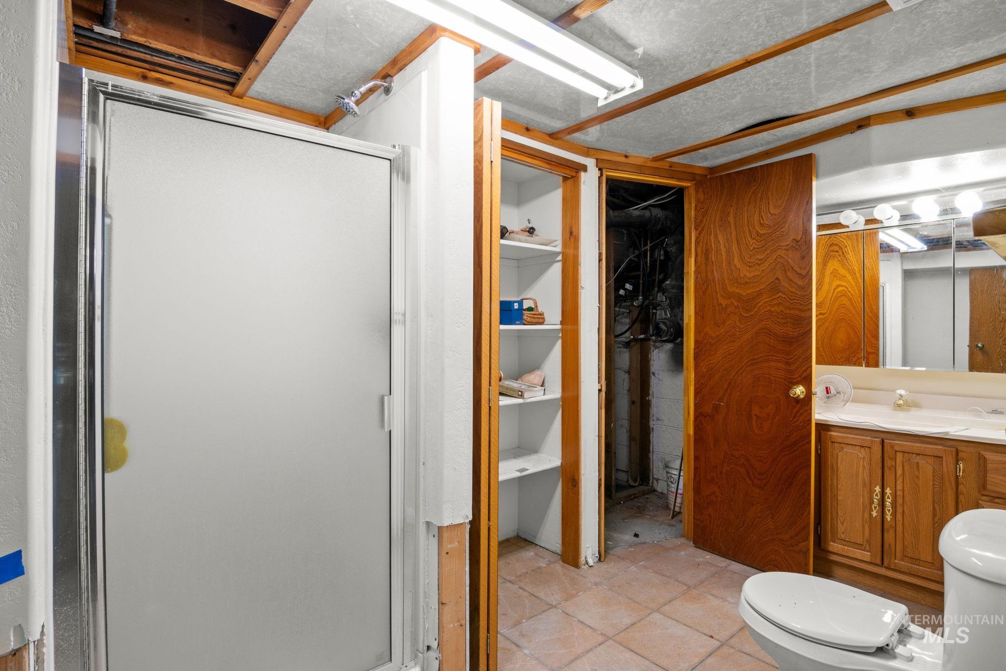 Full bathroom with light tile patterned floors, a shower stall, a closet, and vanity