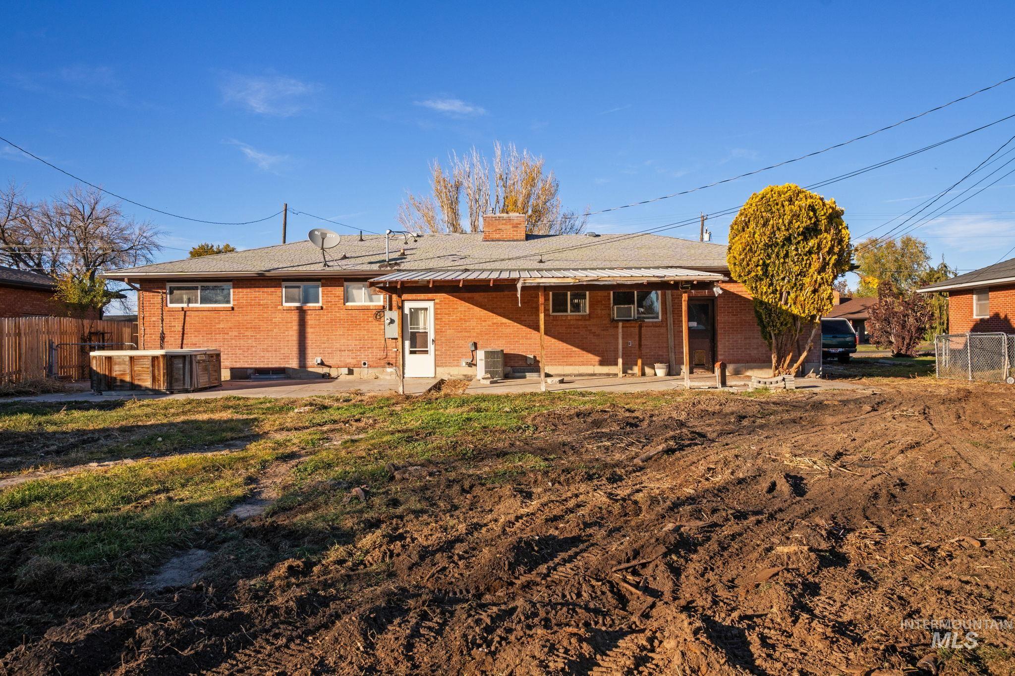 Back of house with a patio, brick siding, and a chimney