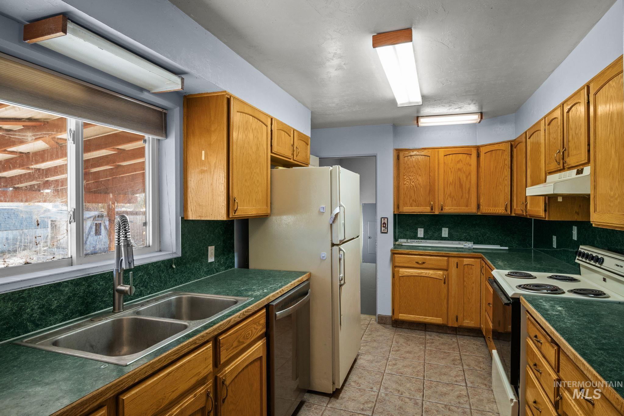 Kitchen with range with electric cooktop, brown cabinetry, and dark countertops