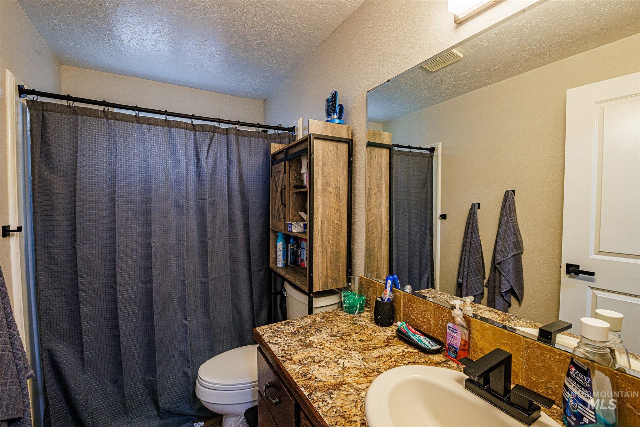 Full bathroom with a textured ceiling, a shower with shower curtain, and vanity
