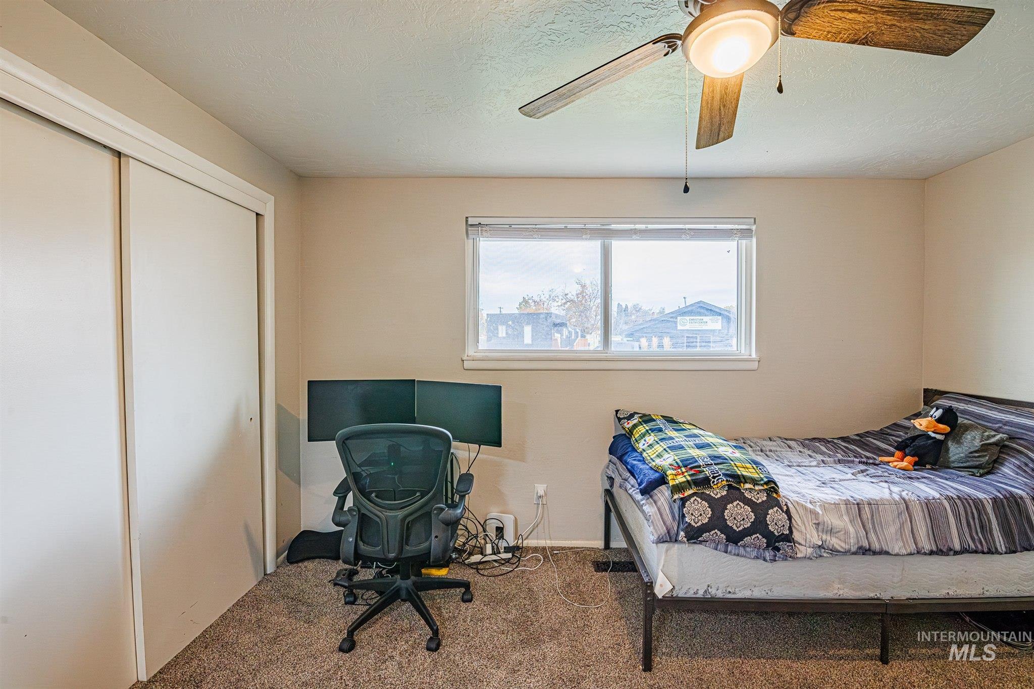 Bedroom with carpet flooring, a desk, ceiling fan, a closet, and a textured ceiling