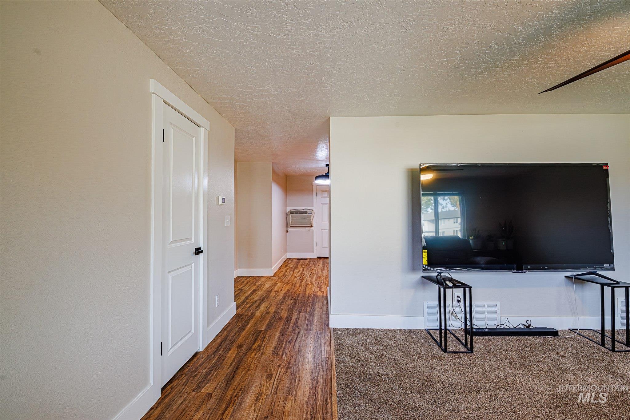Hall featuring a textured ceiling and dark wood-type flooring