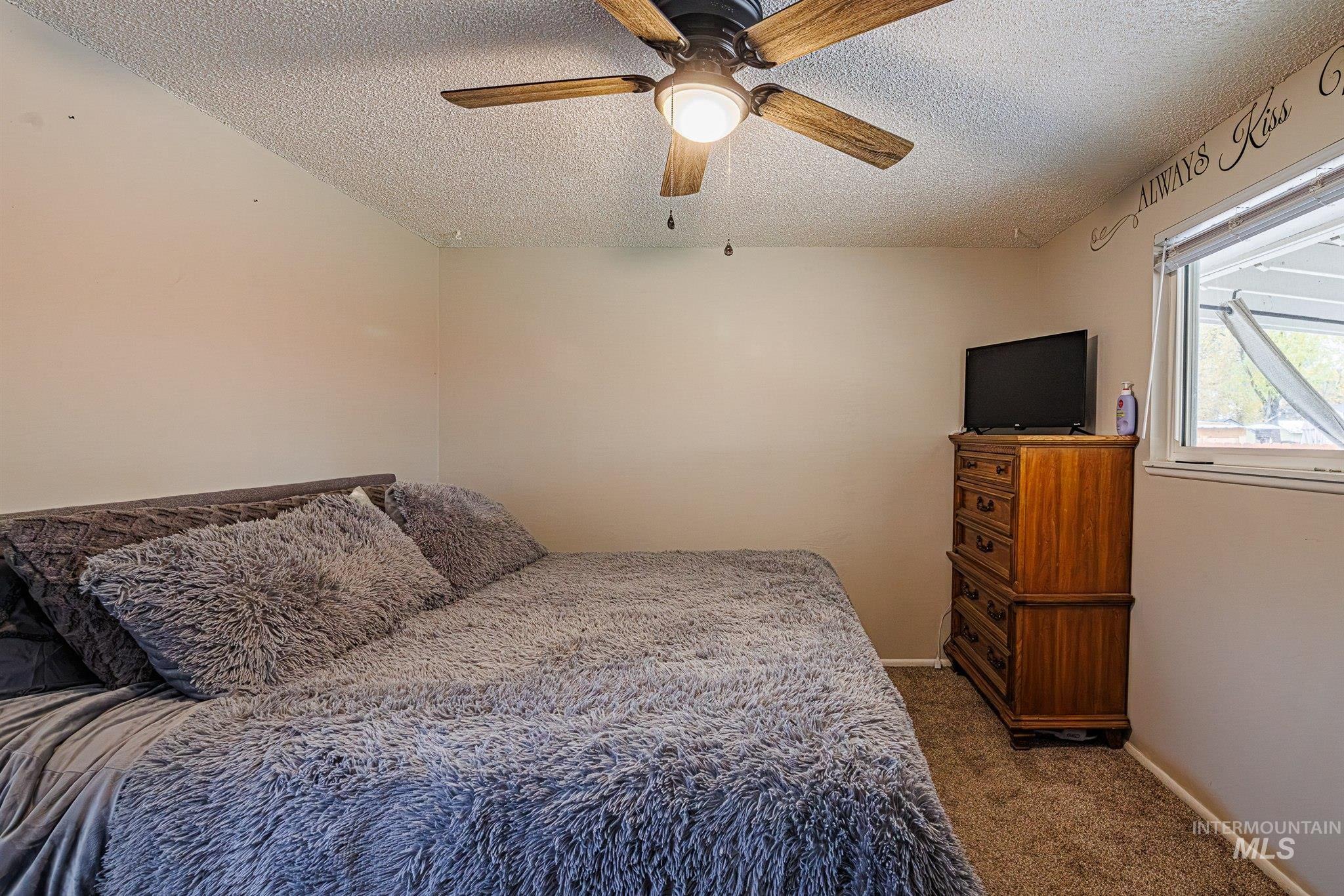 Bedroom featuring dark colored carpet, a textured ceiling, and a ceiling fan