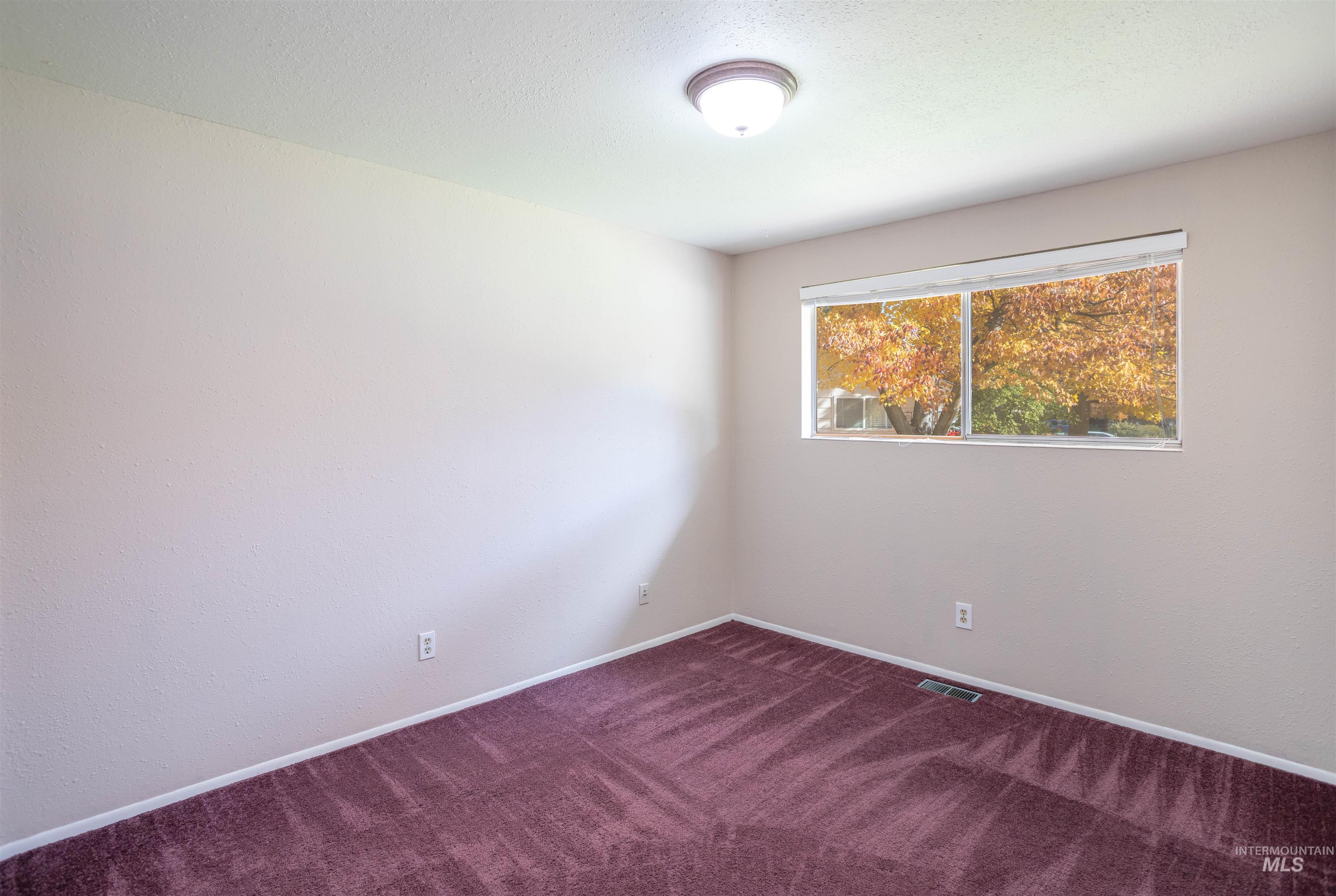 Spare room with baseboards and dark carpet