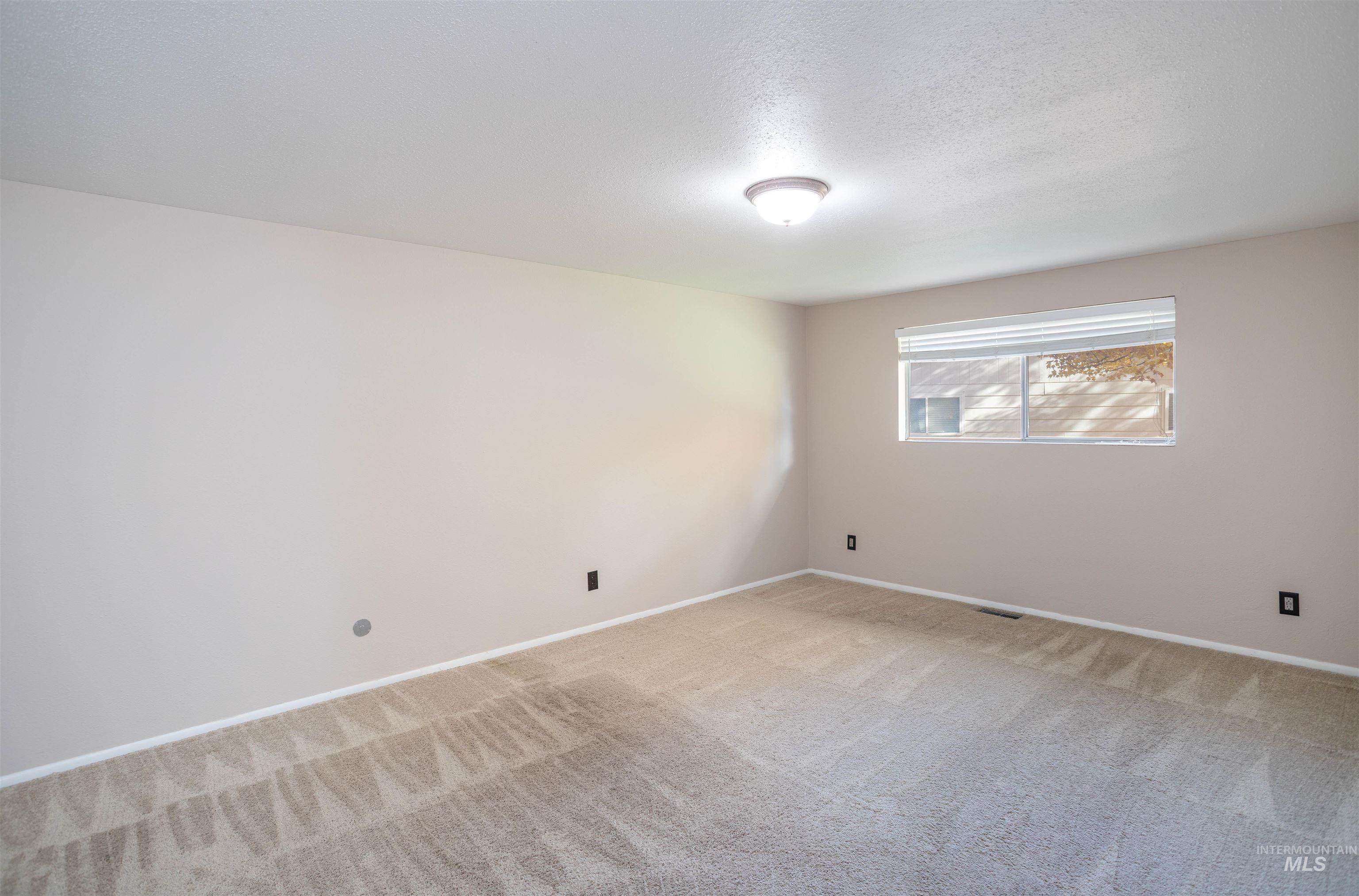 Carpeted empty room featuring baseboards and a textured ceiling