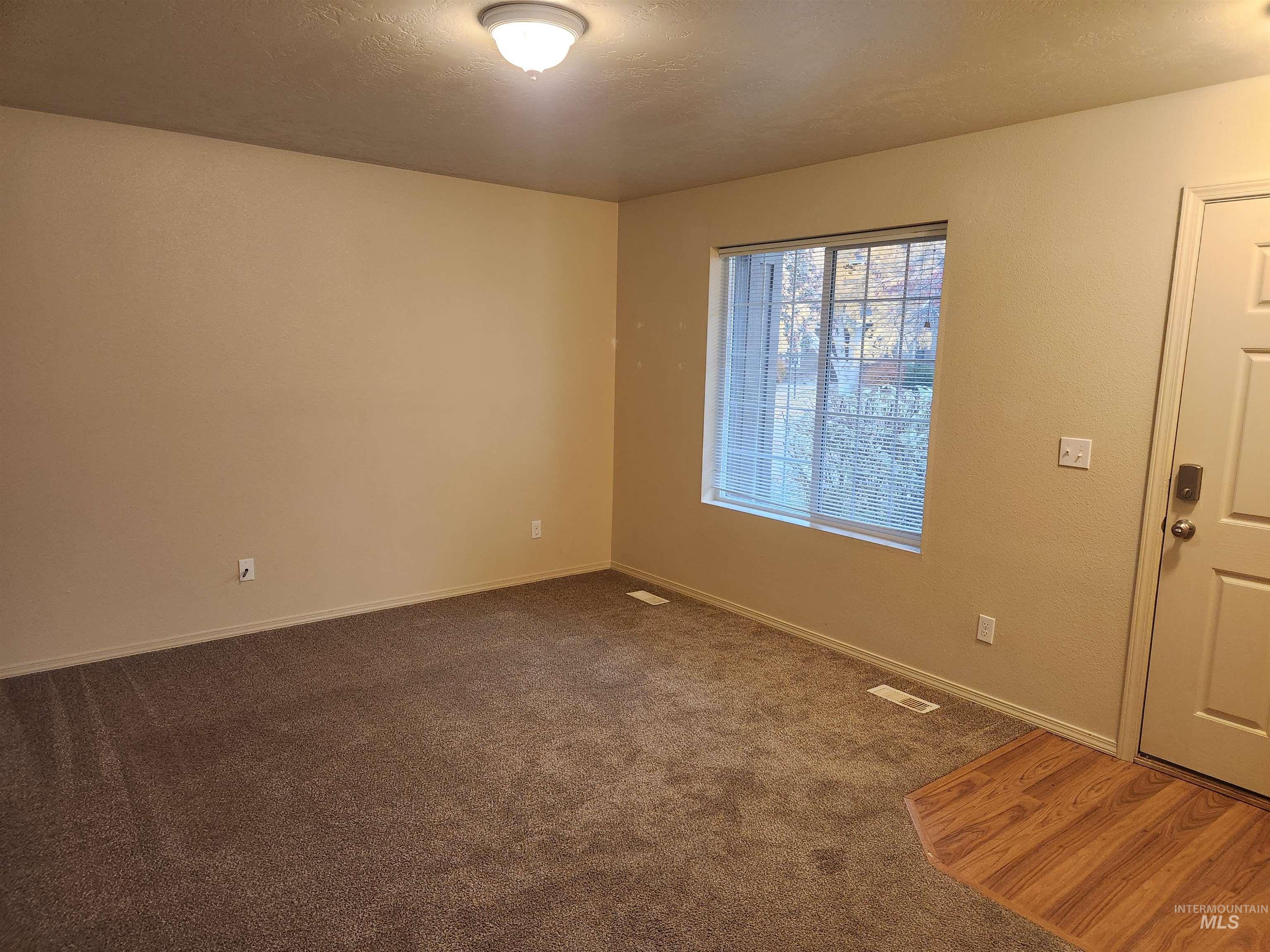 Spare room featuring dark colored carpet and a textured ceiling