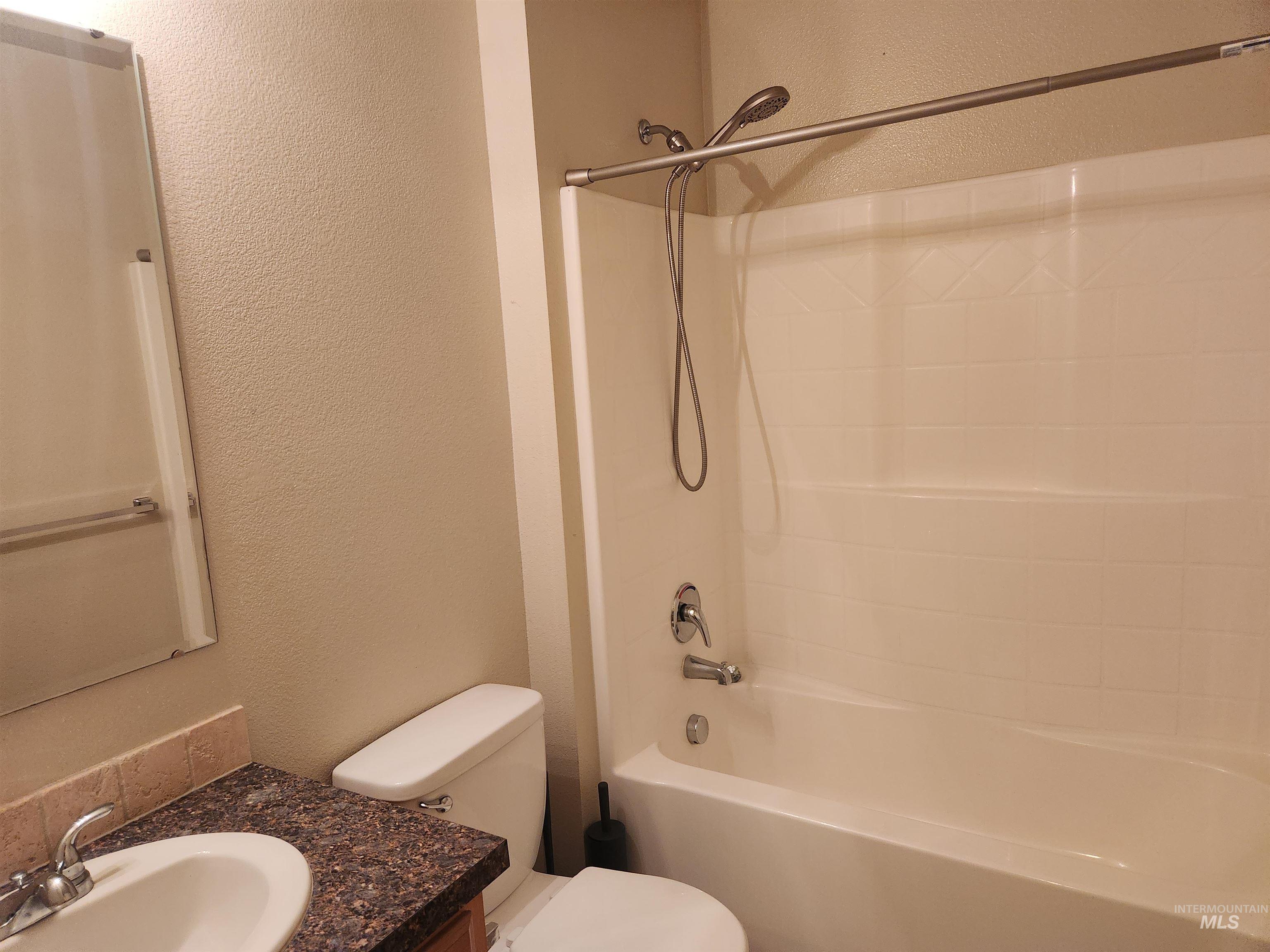 Full bathroom featuring a textured wall, vanity, and shower / tub combination