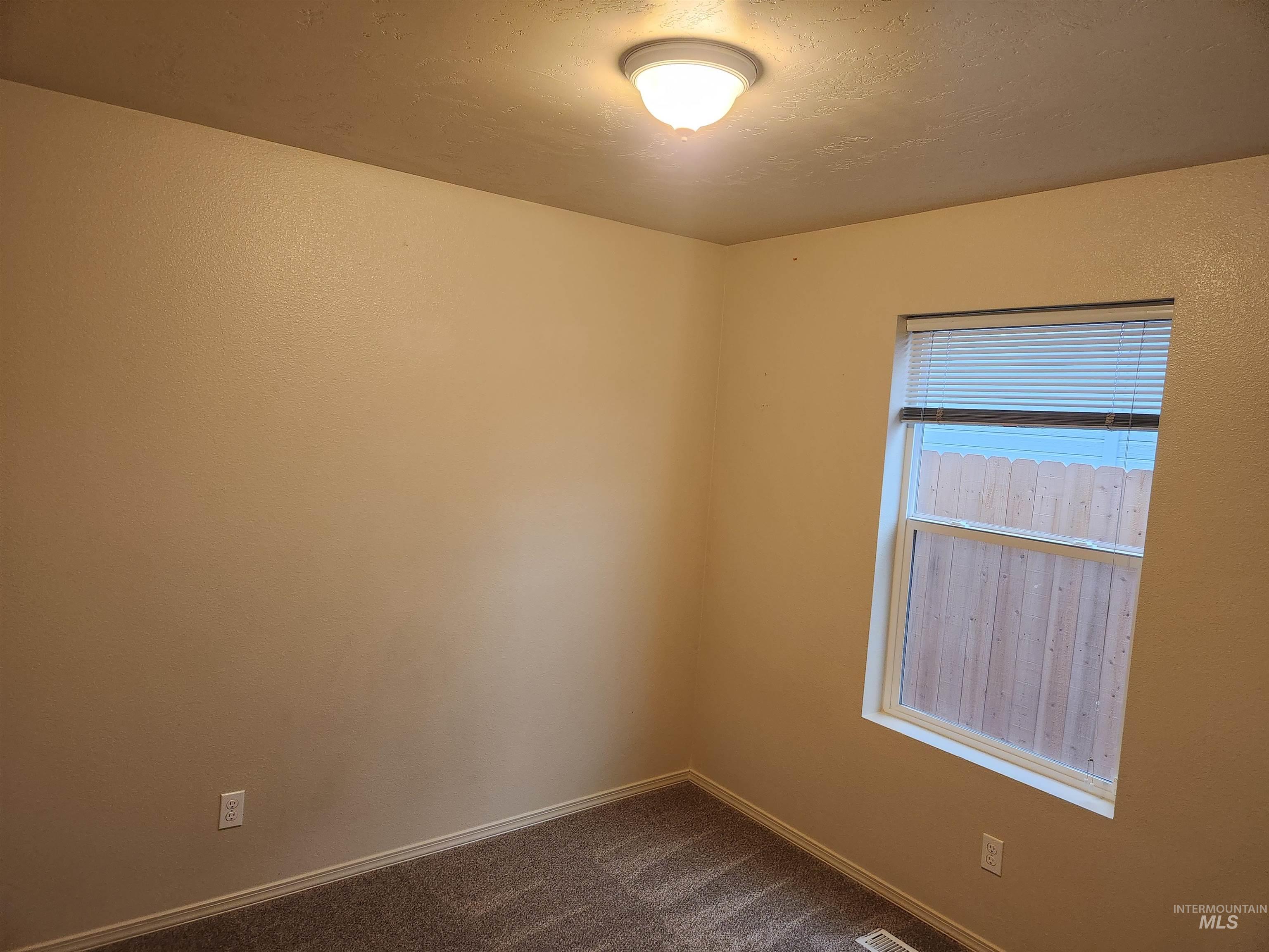 Empty room with dark colored carpet and baseboards