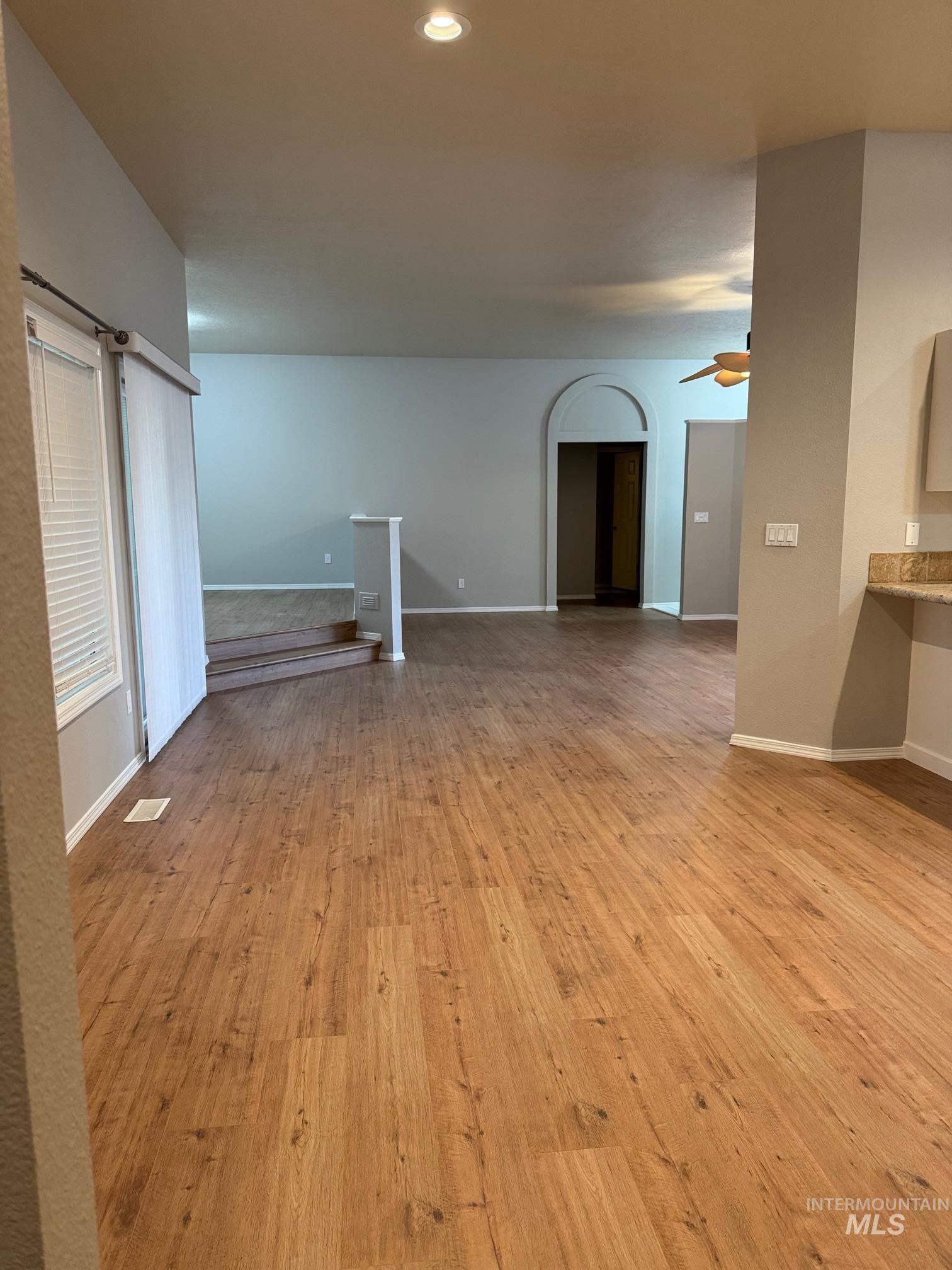 Unfurnished living room with light wood-style flooring, arched walkways, recessed lighting, and a ceiling fan