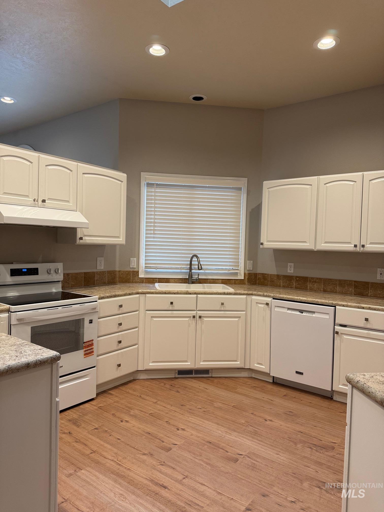 Kitchen with white cabinets, white appliances, recessed lighting, and light wood finished floors