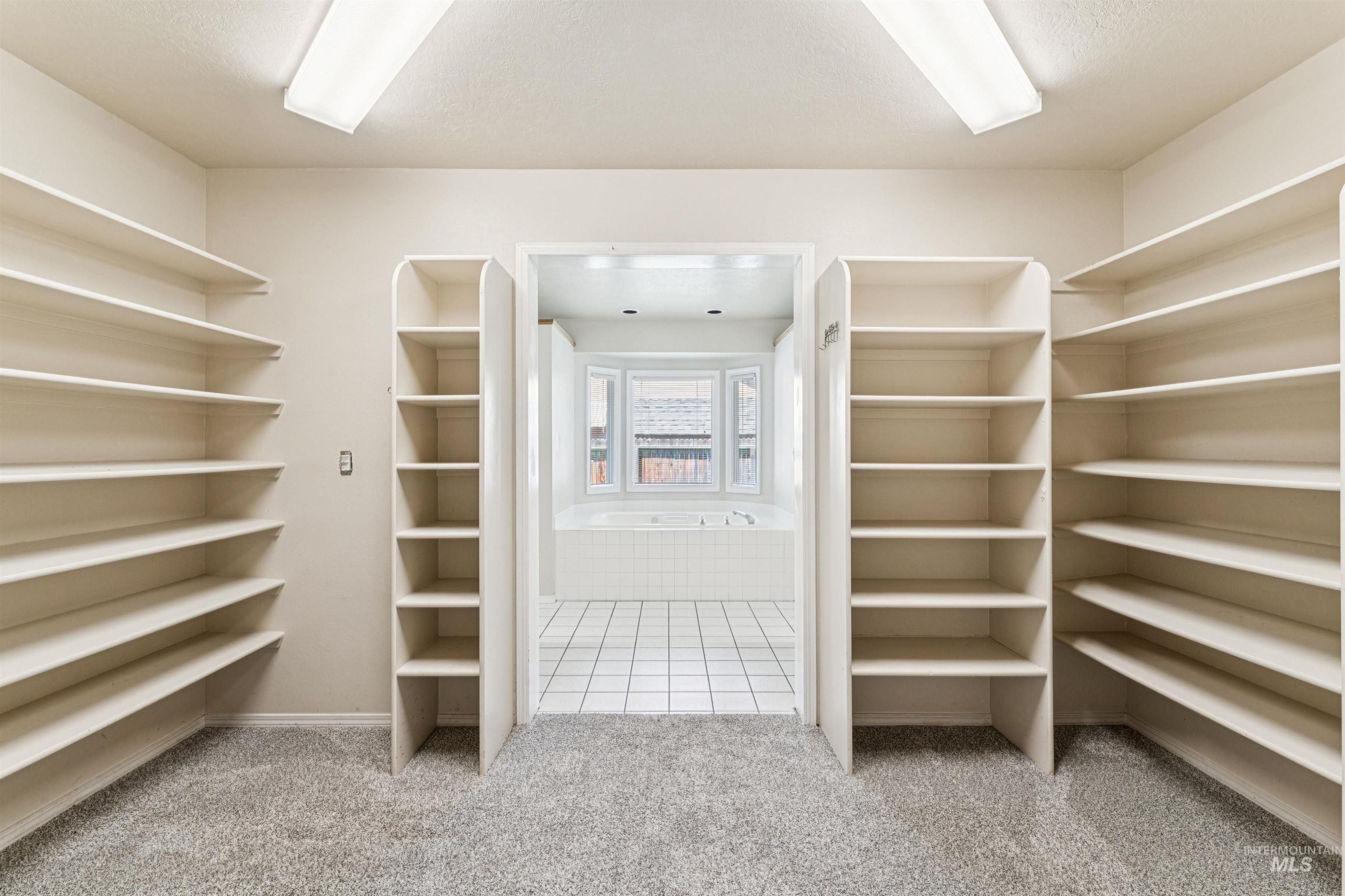 Spacious closet with light colored carpet and light tile patterned floors