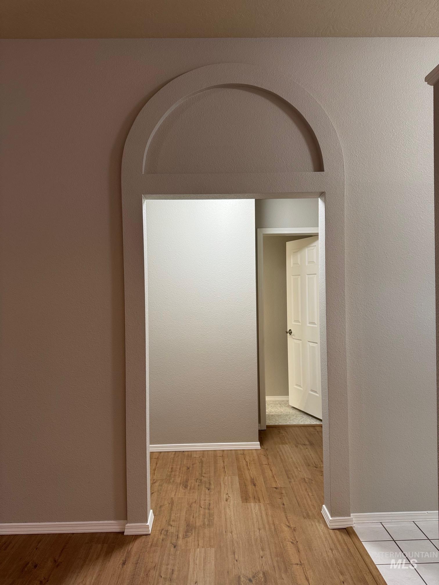 Hall with light wood finished floors and arched walkways