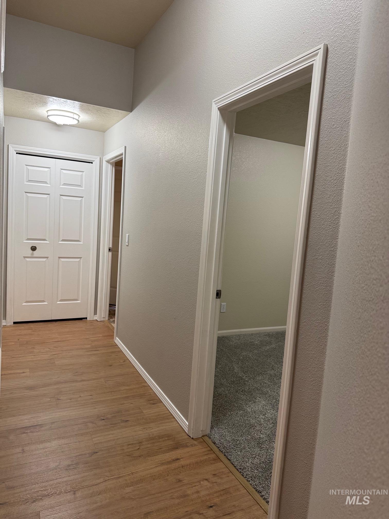 Hall featuring a textured wall and light wood finished floors