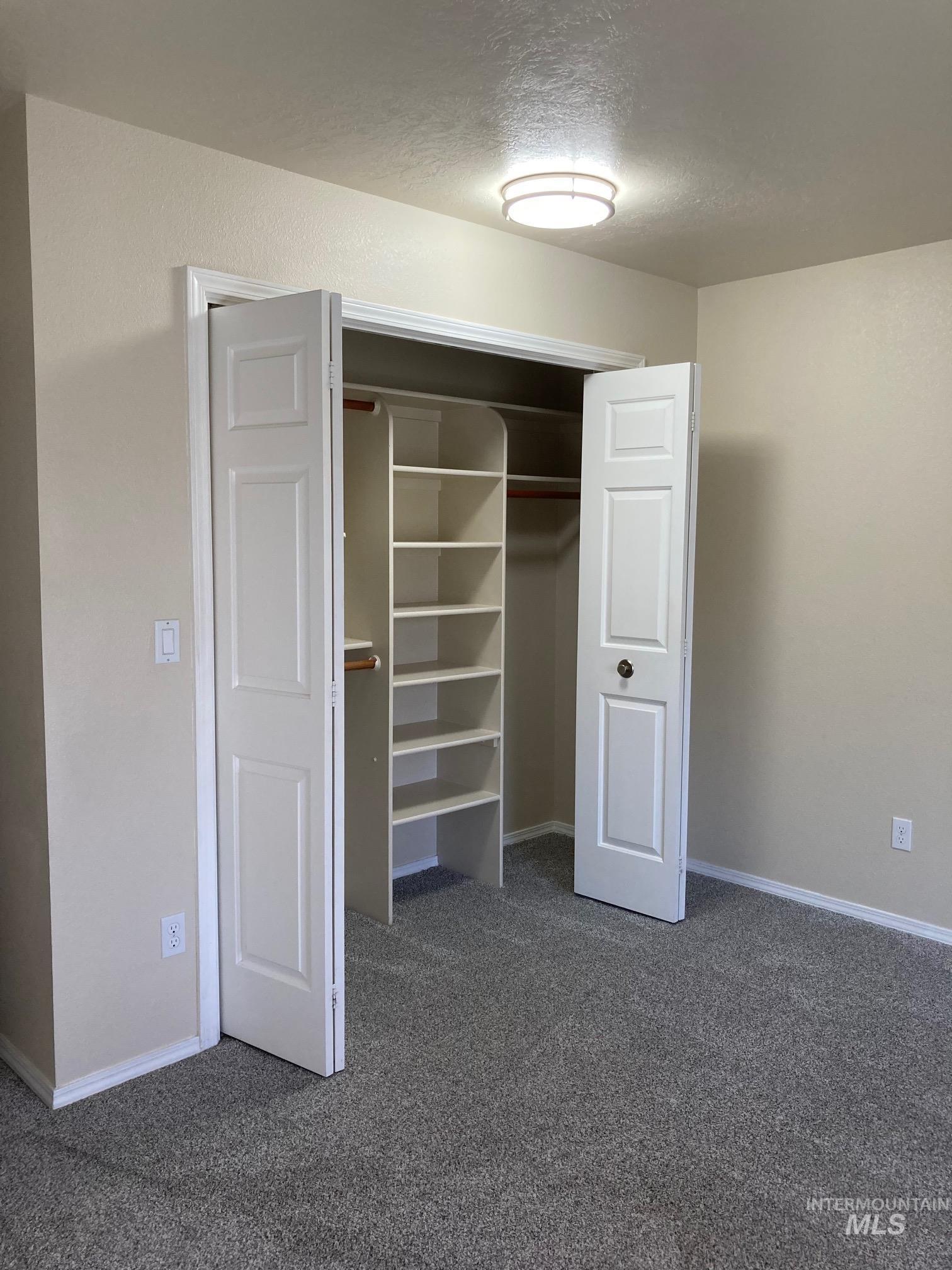 Unfurnished bedroom featuring dark carpet, a textured ceiling, and a closet