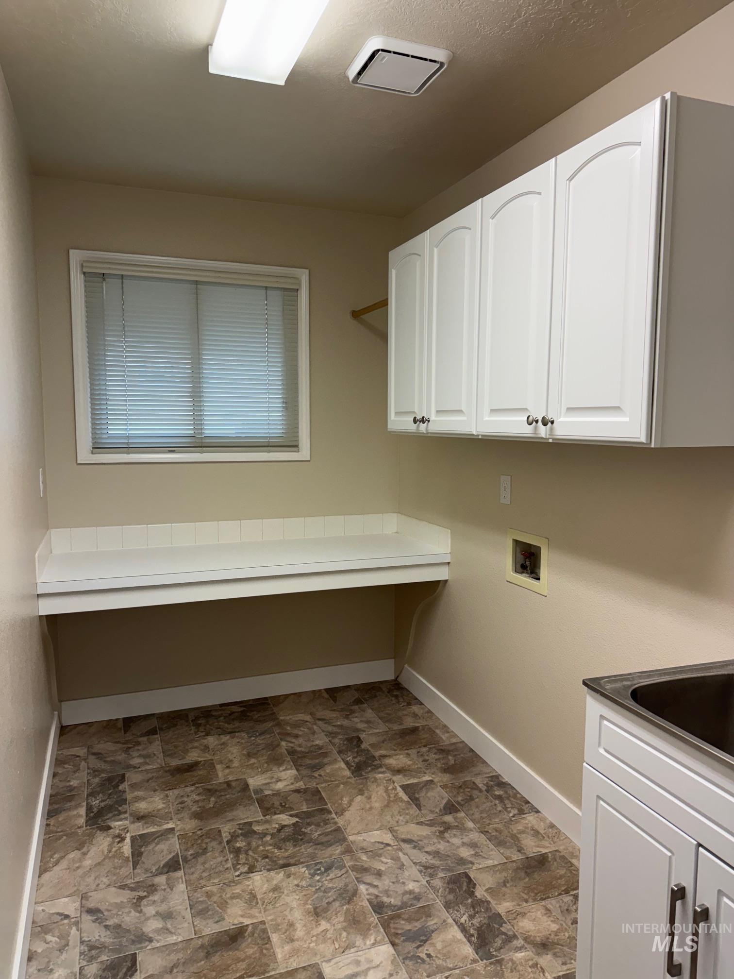 Laundry room featuring cabinet space, washer hookup, and stone finish flooring