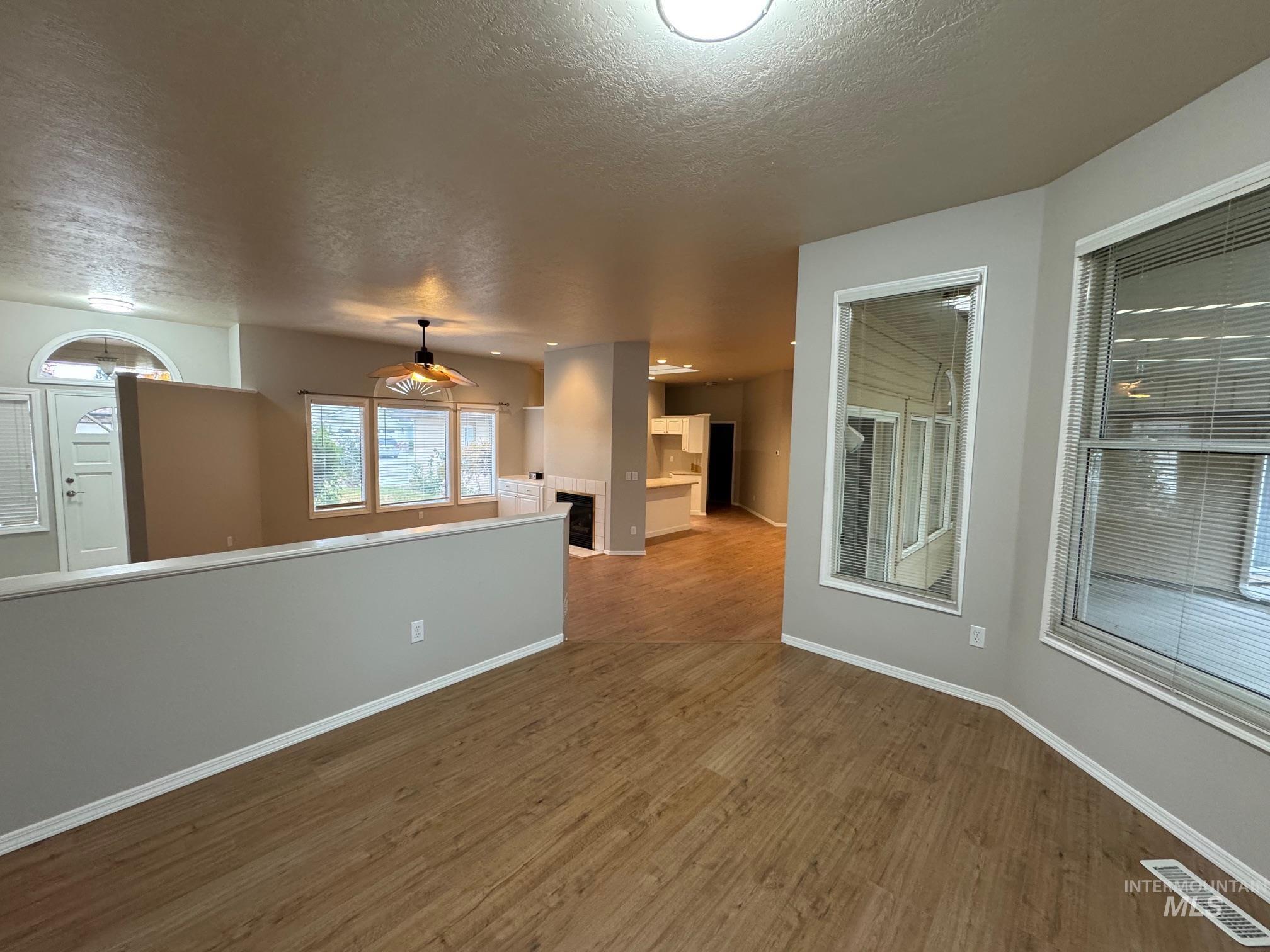 Empty room with dark wood-style floors, a textured ceiling, and a tile fireplace