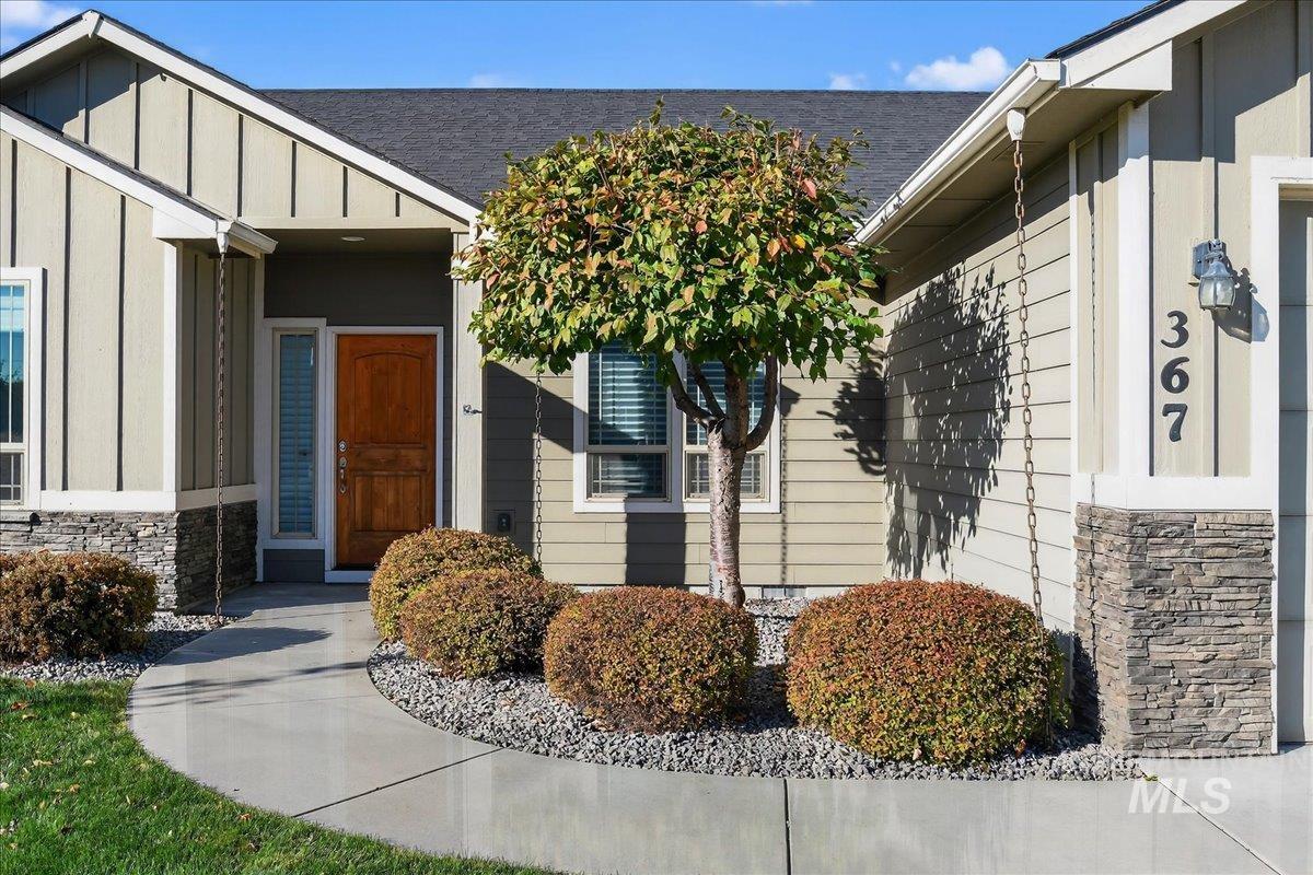 Doorway to property with stone siding, board and batten siding, and a shingled roof
