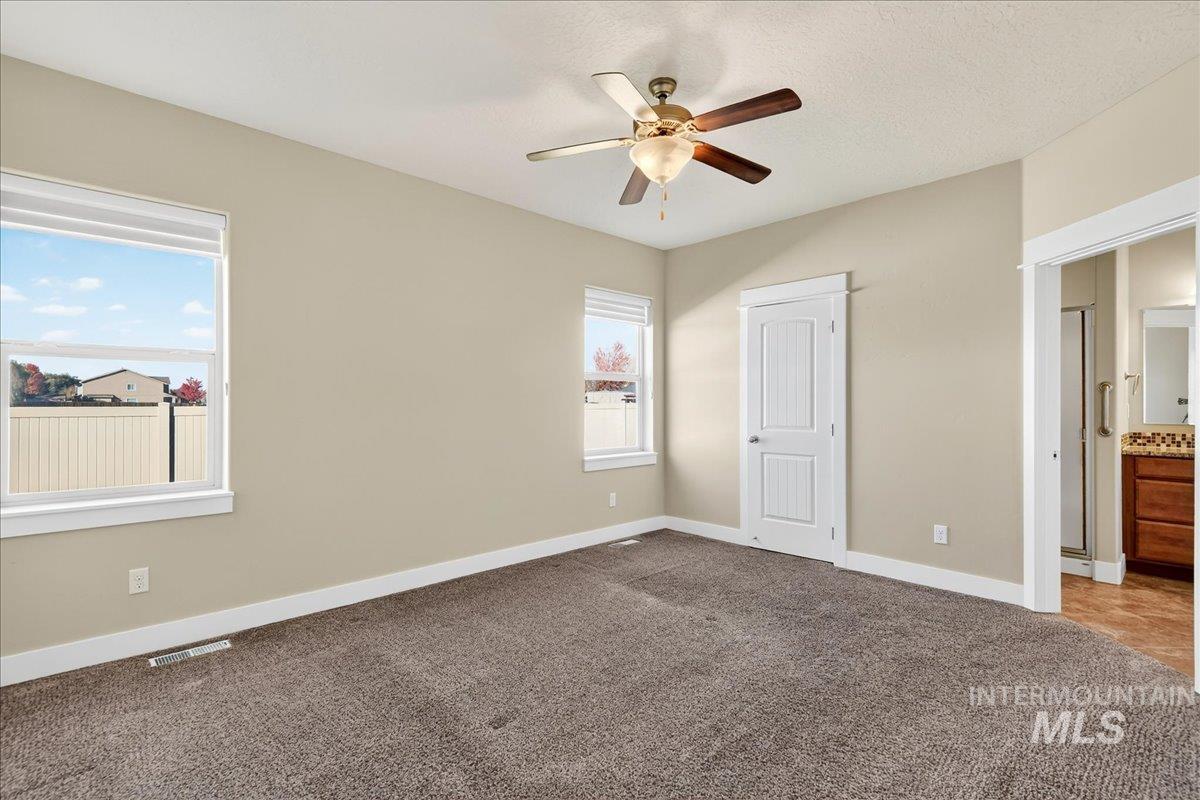 Unfurnished bedroom featuring light colored carpet, a ceiling fan, connected bathroom, and a textured ceiling