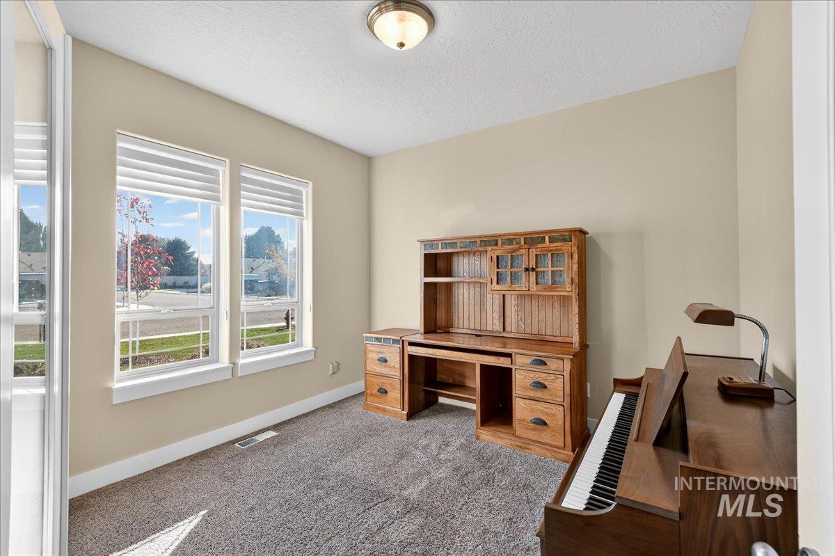 Office area featuring carpet and a textured ceiling