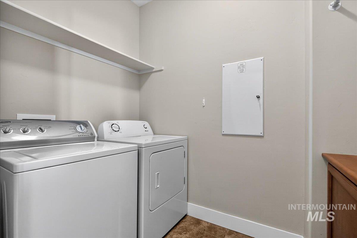 Washroom with washing machine and clothes dryer and dark tile patterned flooring