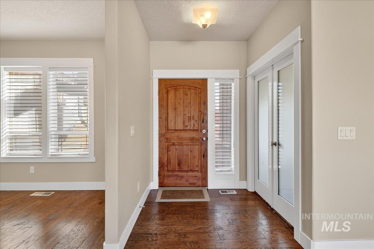 Entrance foyer featuring plenty of natural light, a textured ceiling, dark wood finished floors, and french doors