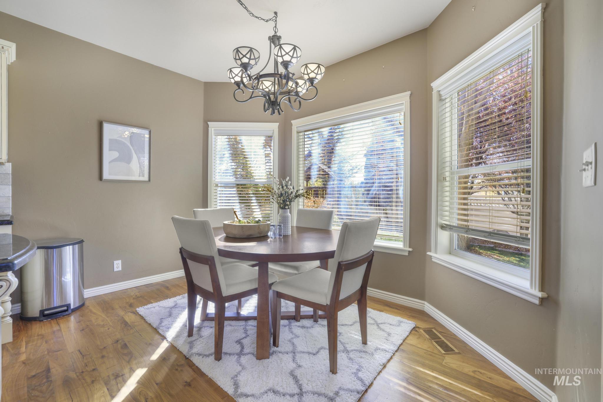 Dining area with 3 Large picture windows, walnut hardwood floors and a chandelier