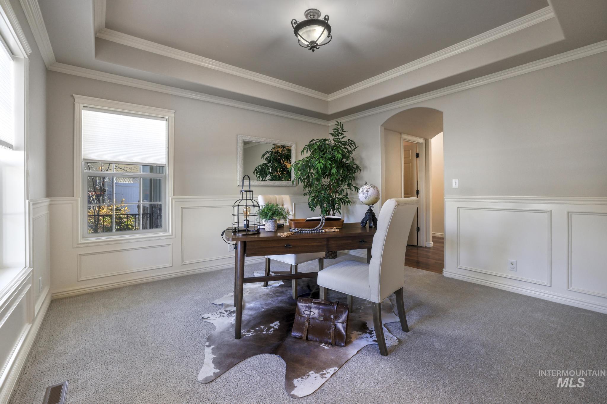 Home office featuring a raised ceiling, new carpet, new paint, arched walkways, wainscoting  and ornamental molding.