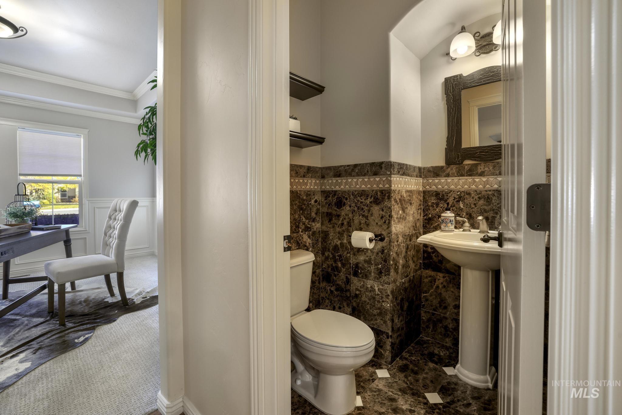 Beautiful powder bathroom off of the kitchen and office, with marble tiled walls and floor, pedestal sink and custom shelving.