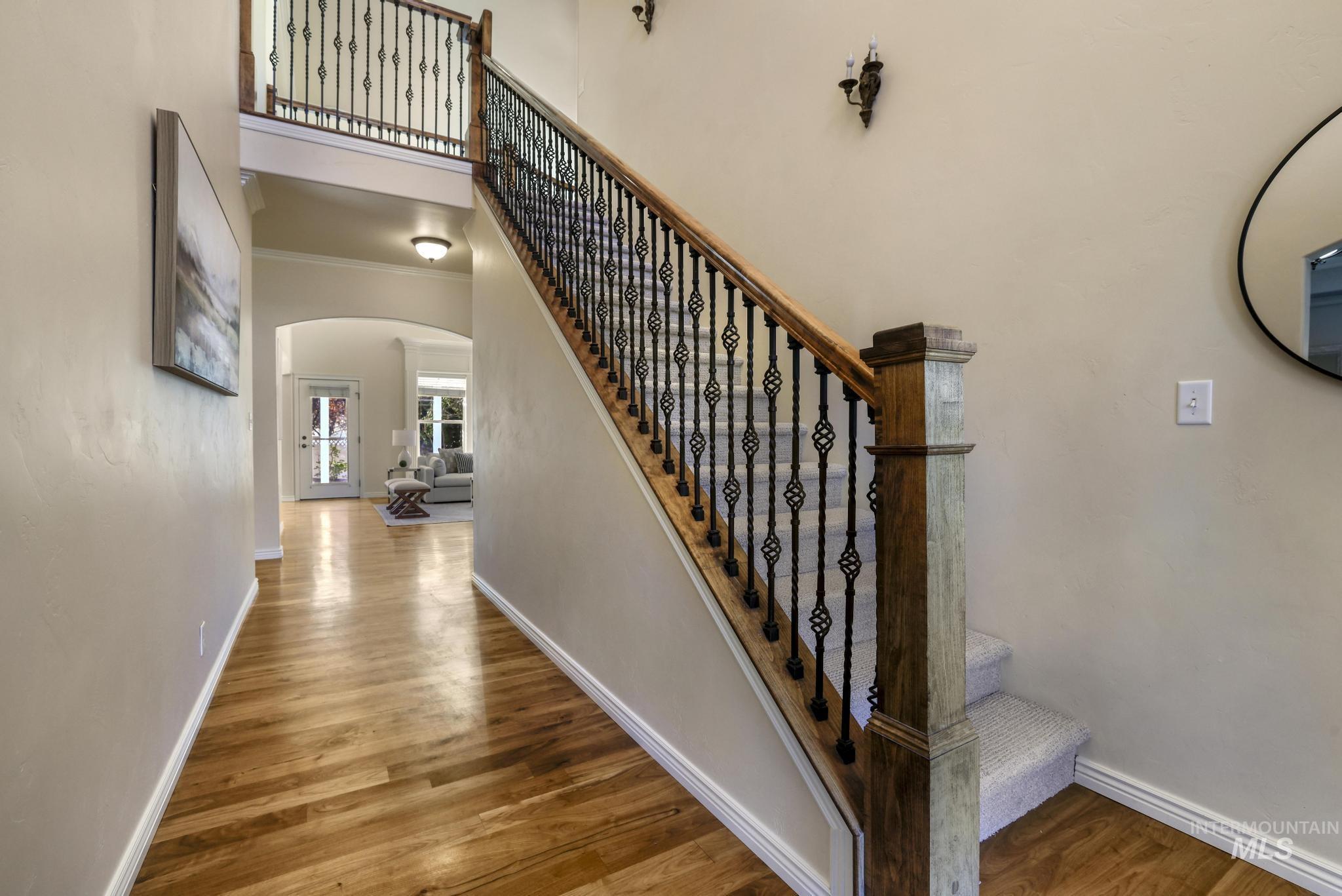 Stairs with arched walkways, Walnut floors, a towering ceiling, and ornamental molding