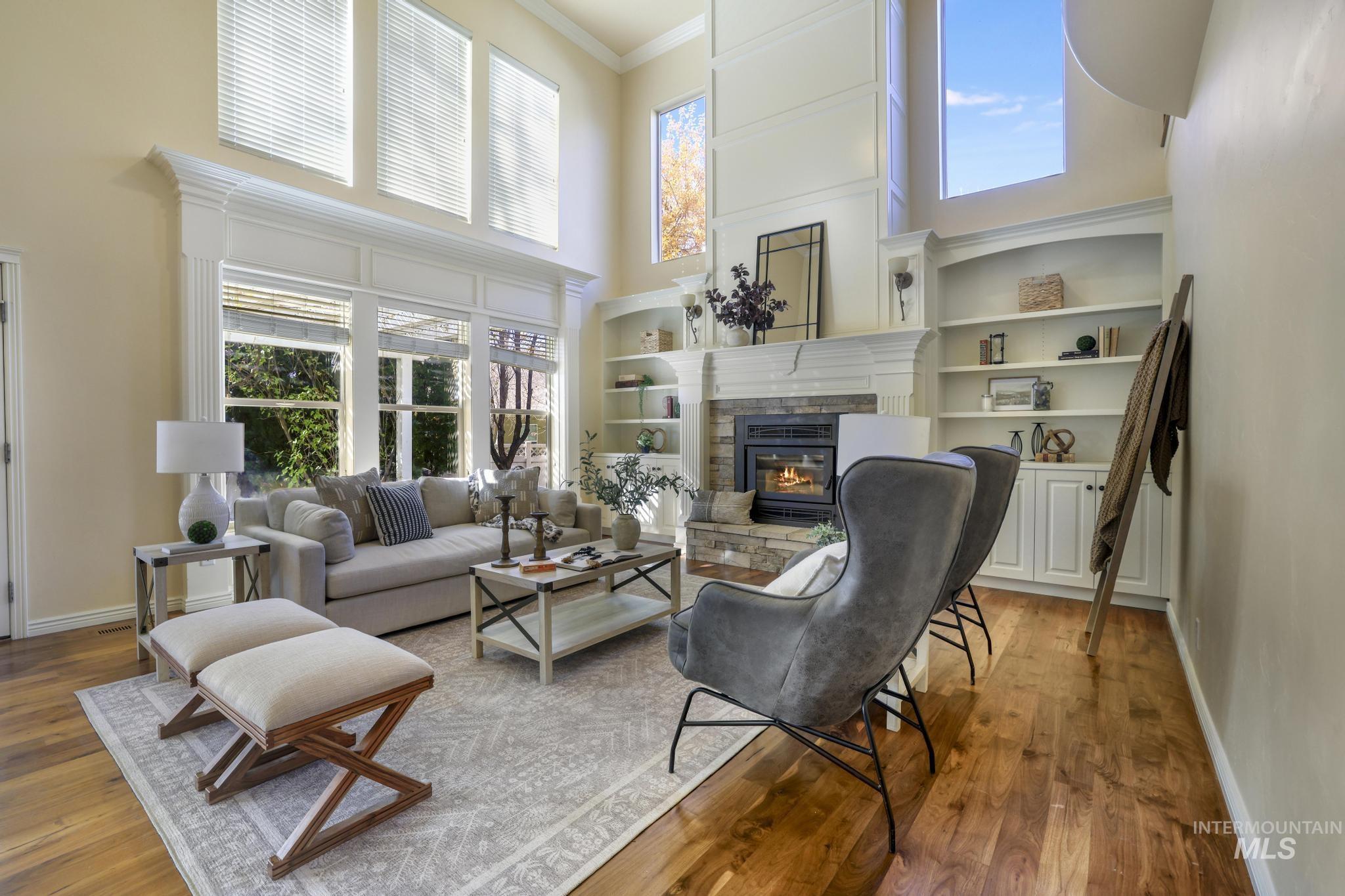 Living room featuring a high ceiling, plenty of natural light, crown molding, wood burning fire place, and walnut Hardwood floors