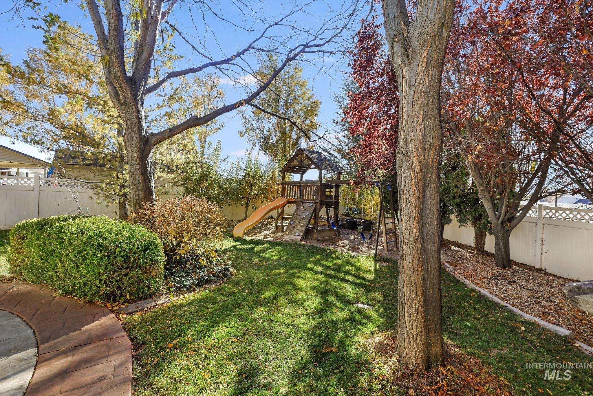 Fenced backyard with a gazebo, a playground, and a patio area