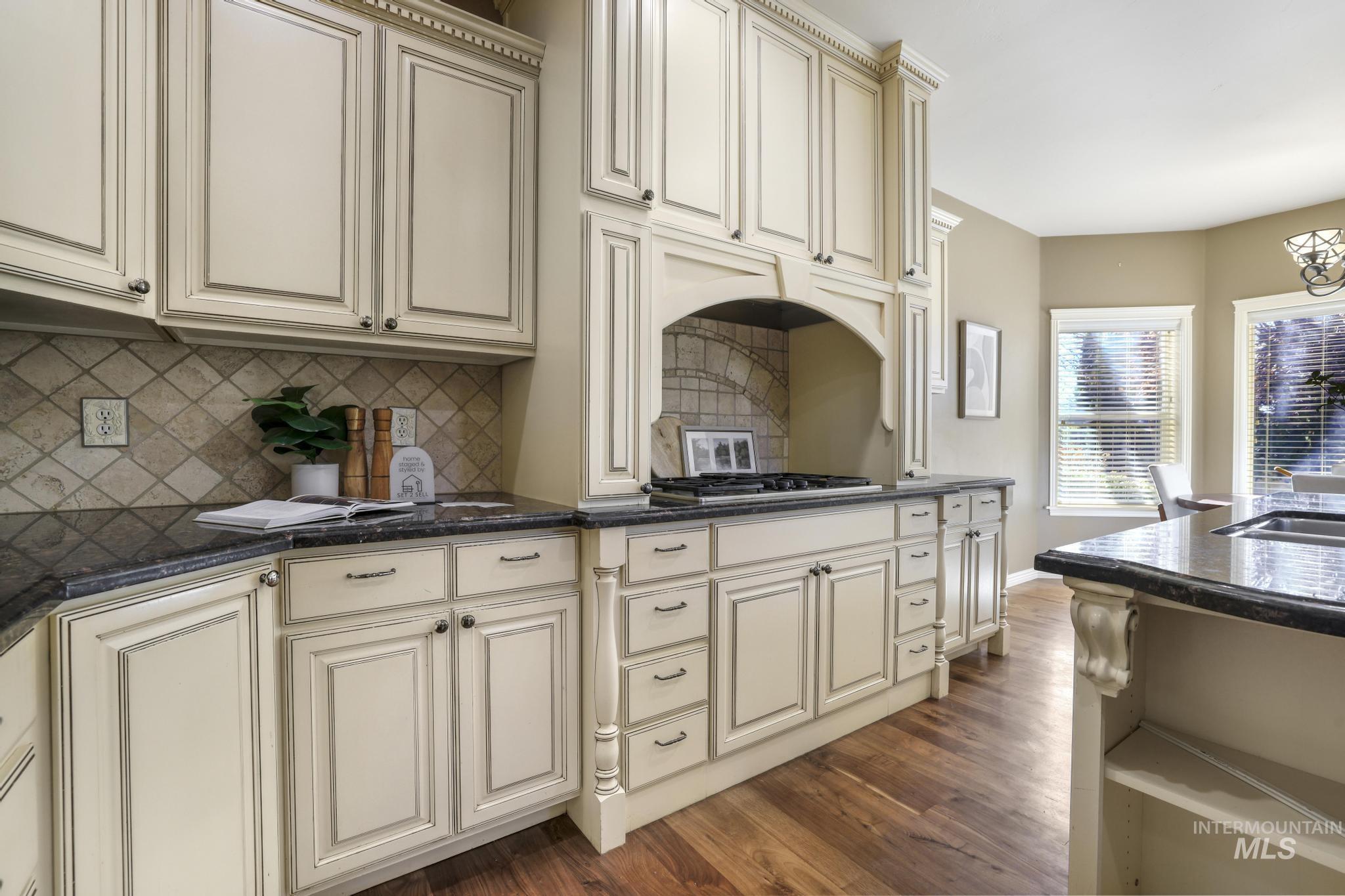 Kitchen with Walnut hardwood floors, gas cook top, integrated ventilation hood system, granite countertops, tile back splash