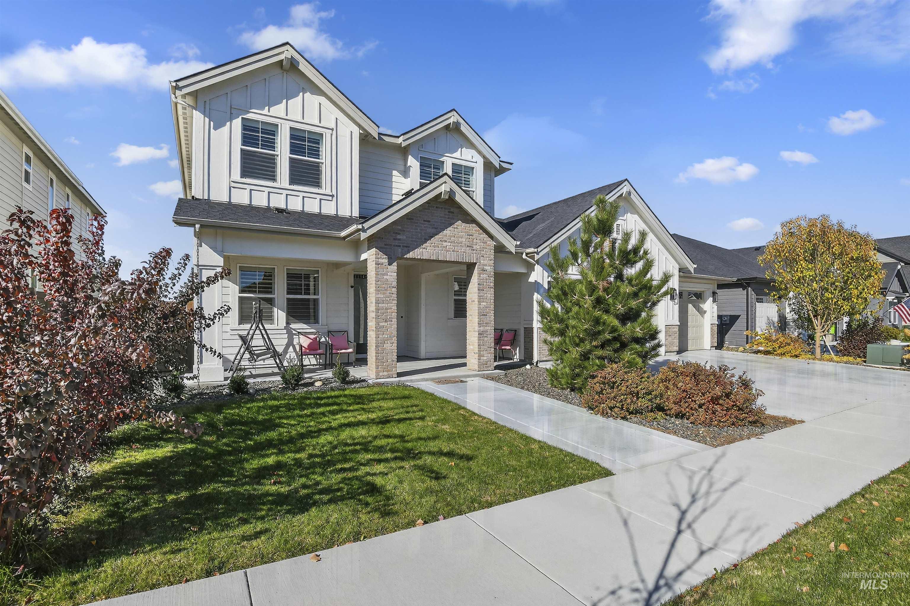 View of front of house with board and batten siding, covered porch, concrete driveway, and a front yard