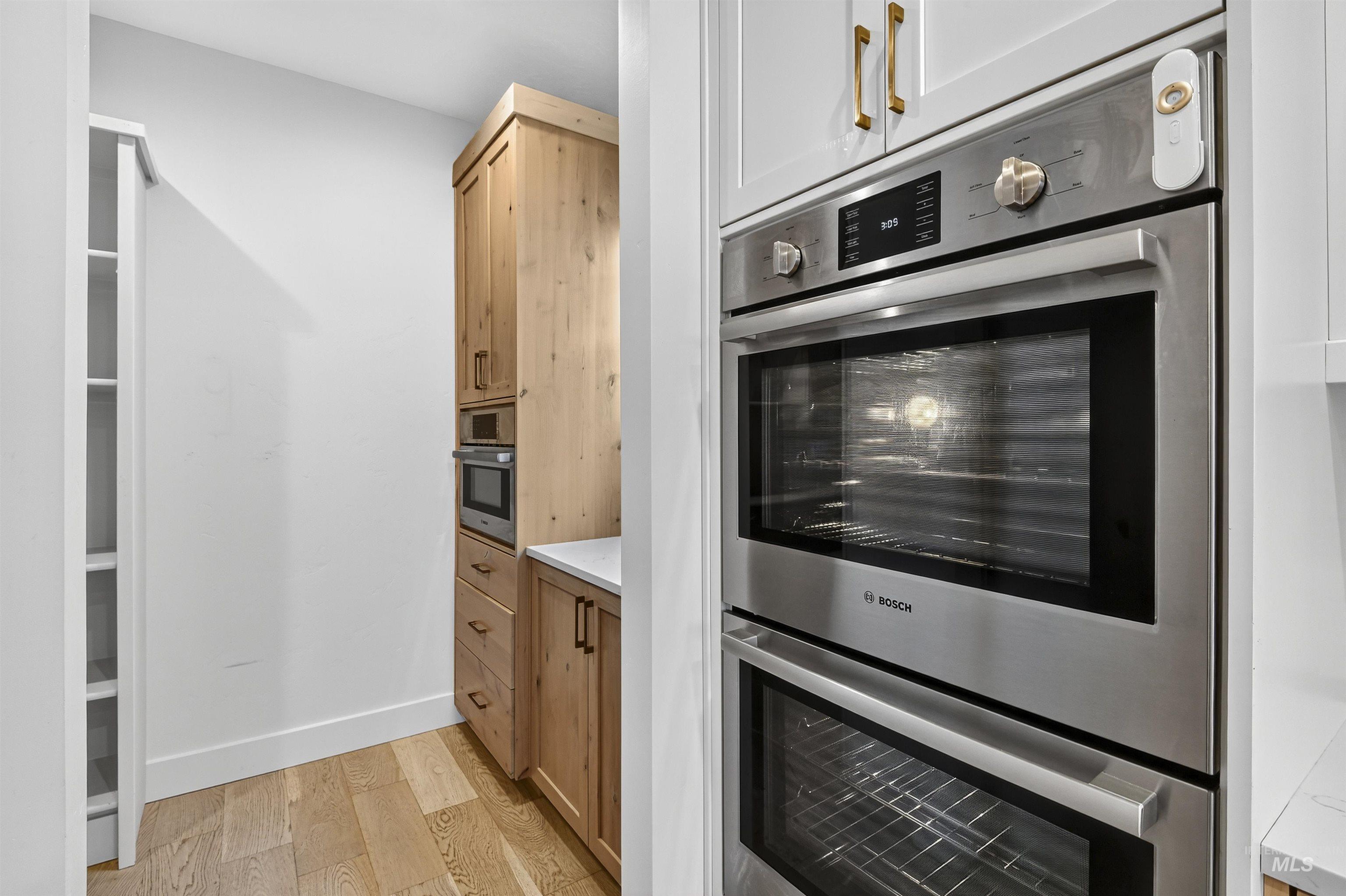Kitchen with double oven and light wood-style flooring