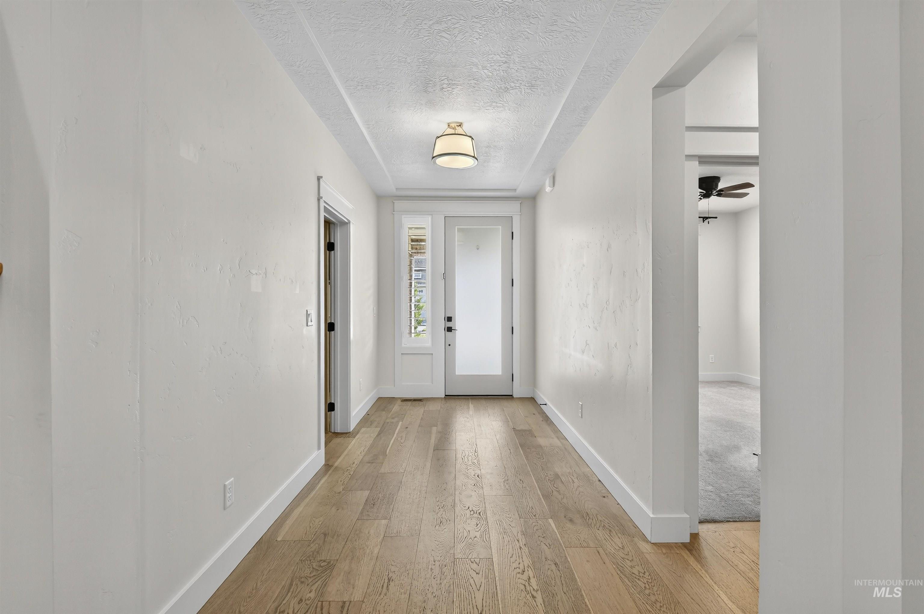 Doorway featuring wood-type flooring, a textured ceiling, and a ceiling fan
