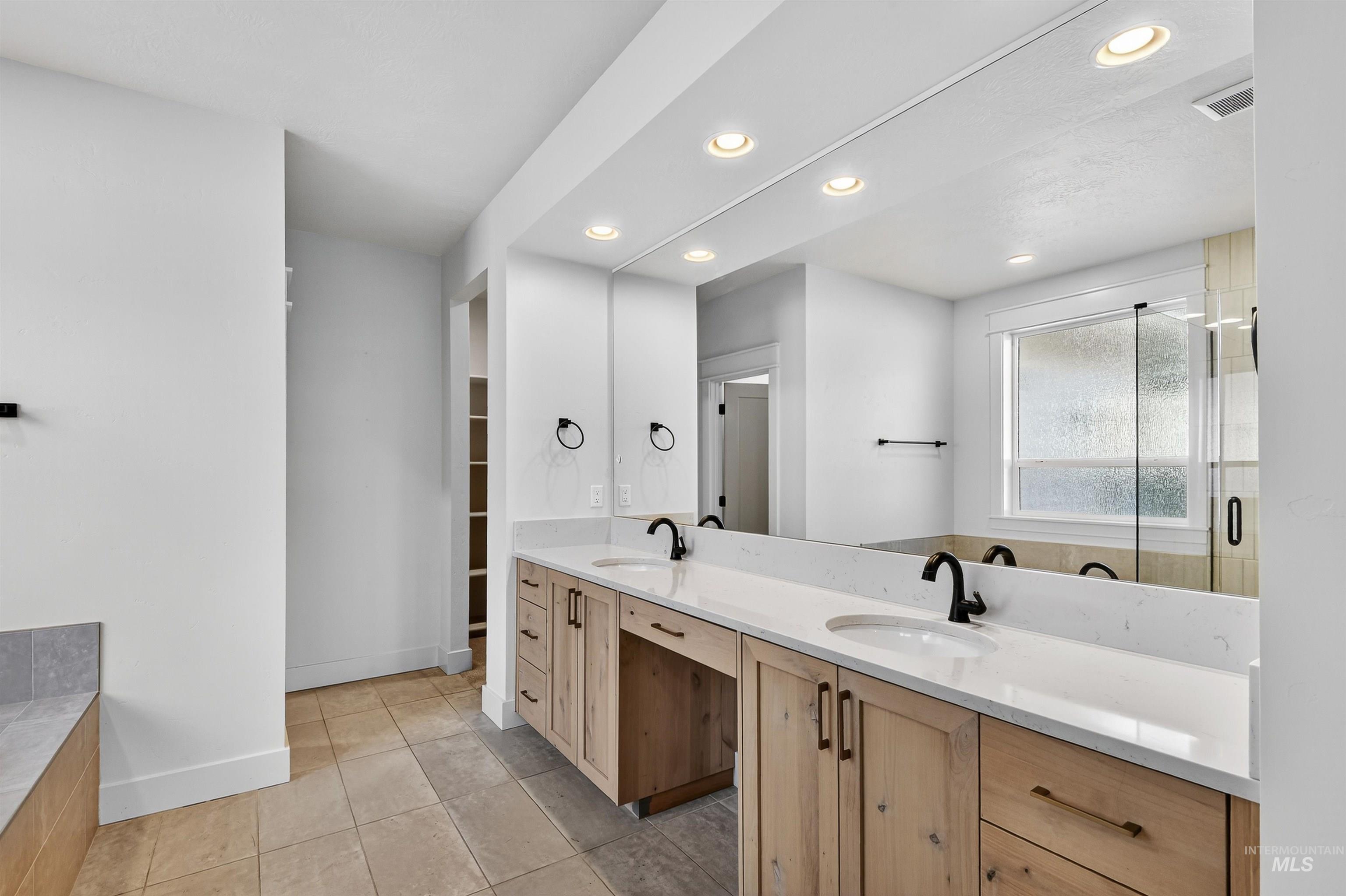 Full bathroom featuring double vanity, recessed lighting, light tile patterned flooring, a stall shower, and a spacious closet