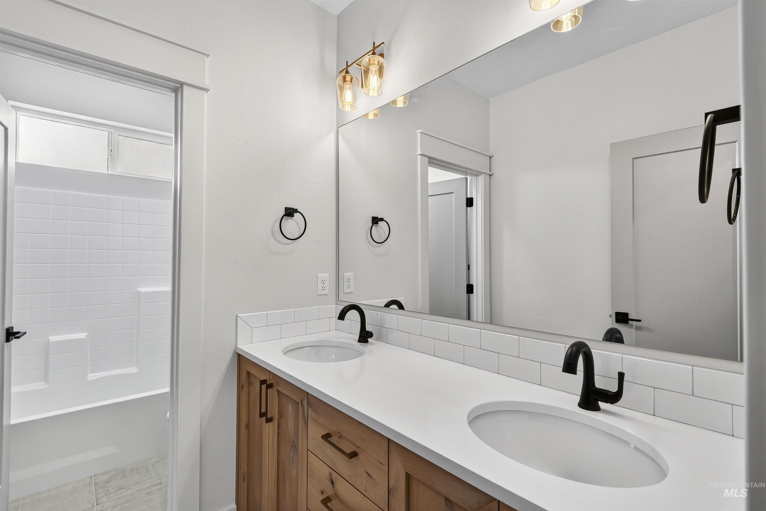 Bathroom with double vanity, shower / bathtub combination, and light tile patterned flooring