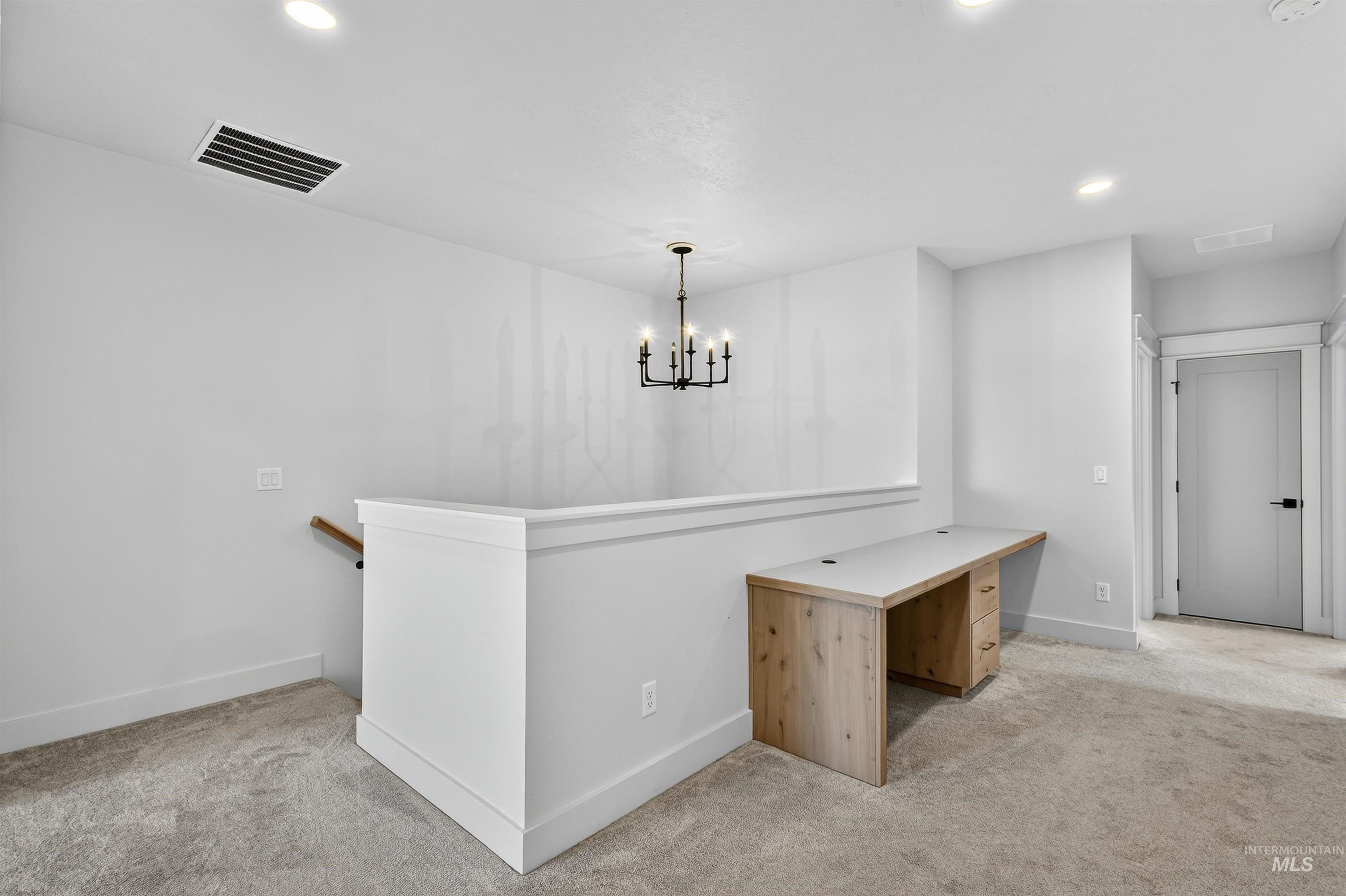 Hallway featuring light carpet, recessed lighting, an upstairs landing, and a chandelier
