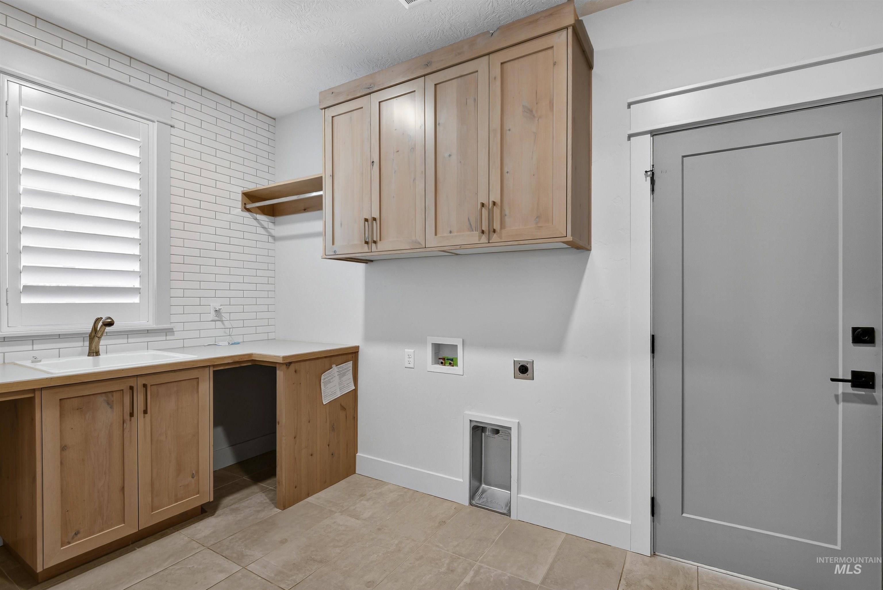 Washroom with hookup for a washing machine, light tile patterned flooring, electric dryer hookup, and cabinet space