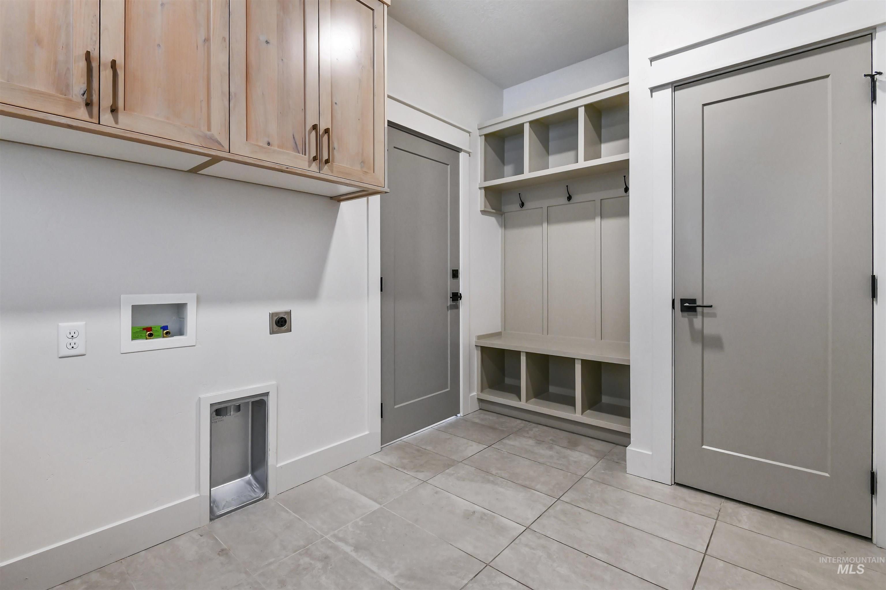 Washroom featuring light tile patterned floors, electric dryer hookup, cabinet space, and washer hookup