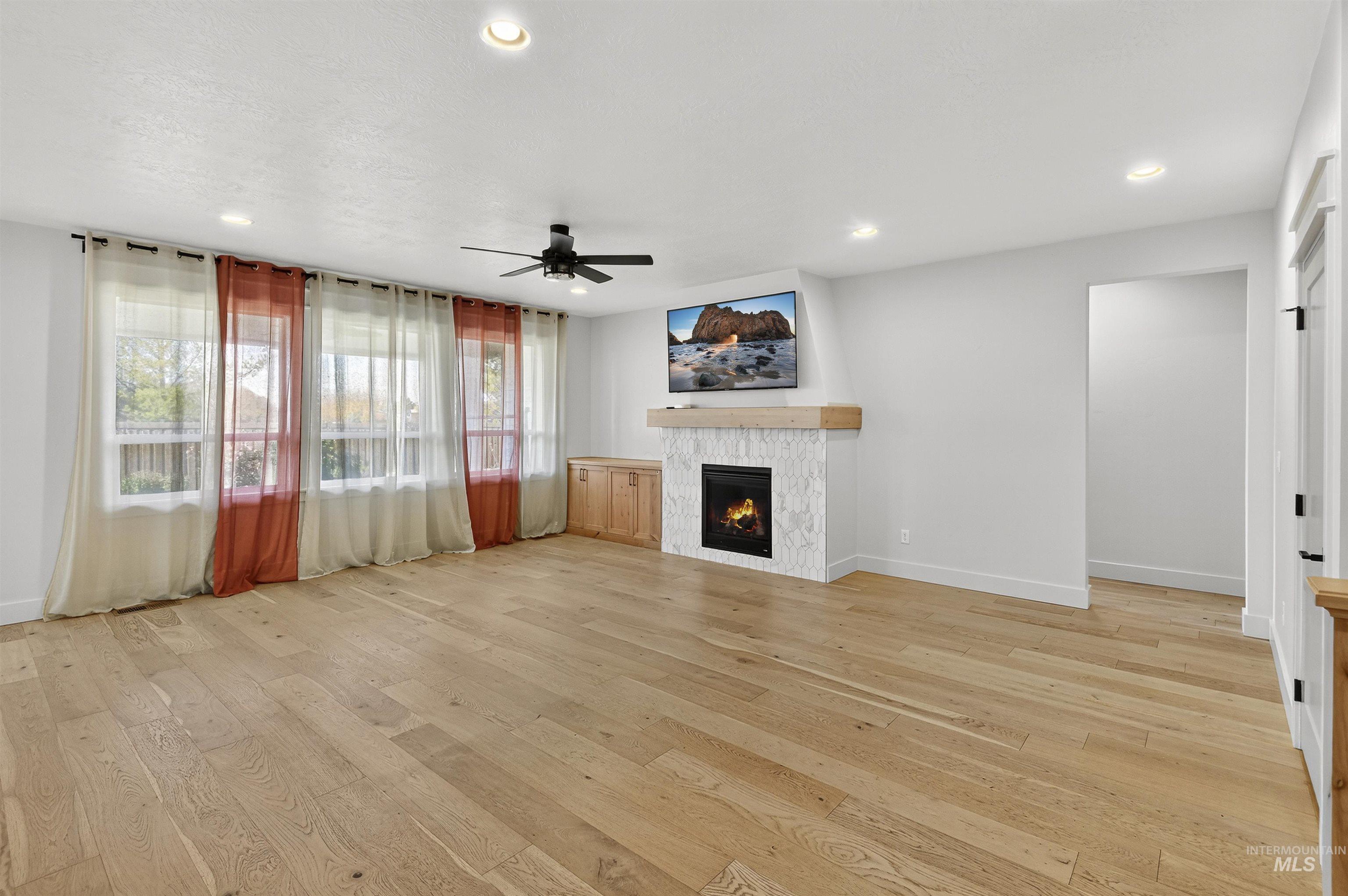Unfurnished living room with a fireplace, light wood finished floors, recessed lighting, and ceiling fan