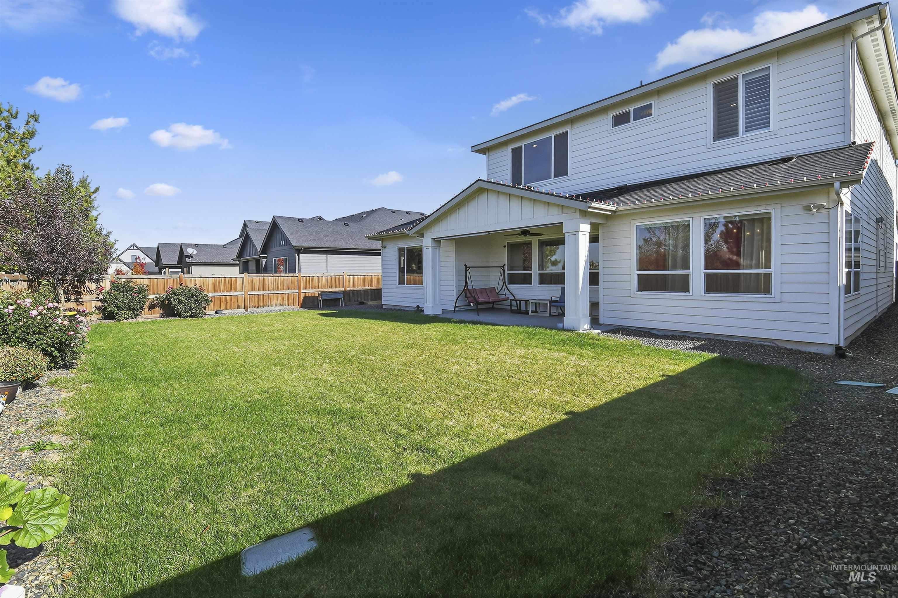 Rear view of house featuring a patio area, a fenced backyard, and roof with shingles