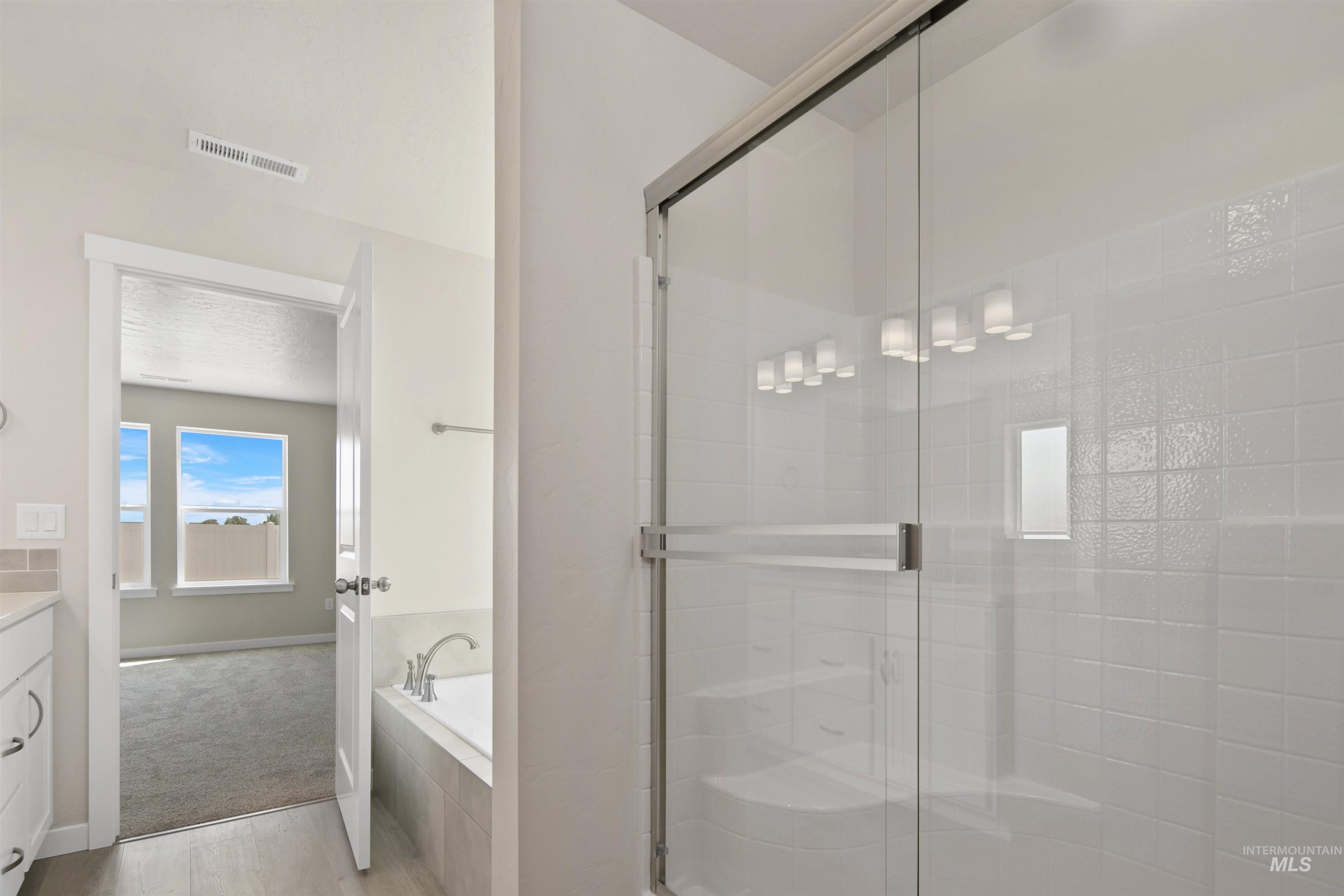 Bathroom with vanity, a bath, a shower stall, and light wood-style floors