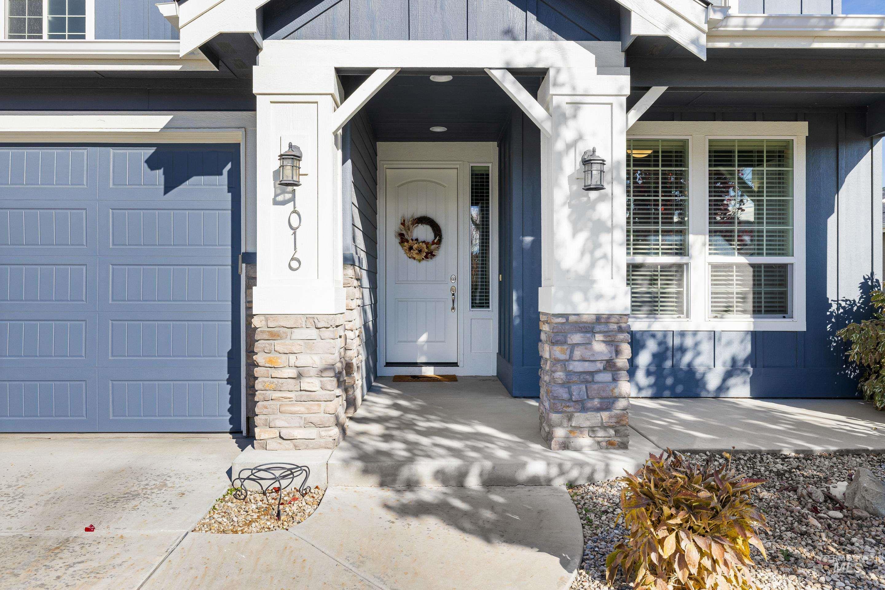 Doorway to property featuring a garage, stone siding, and a porch