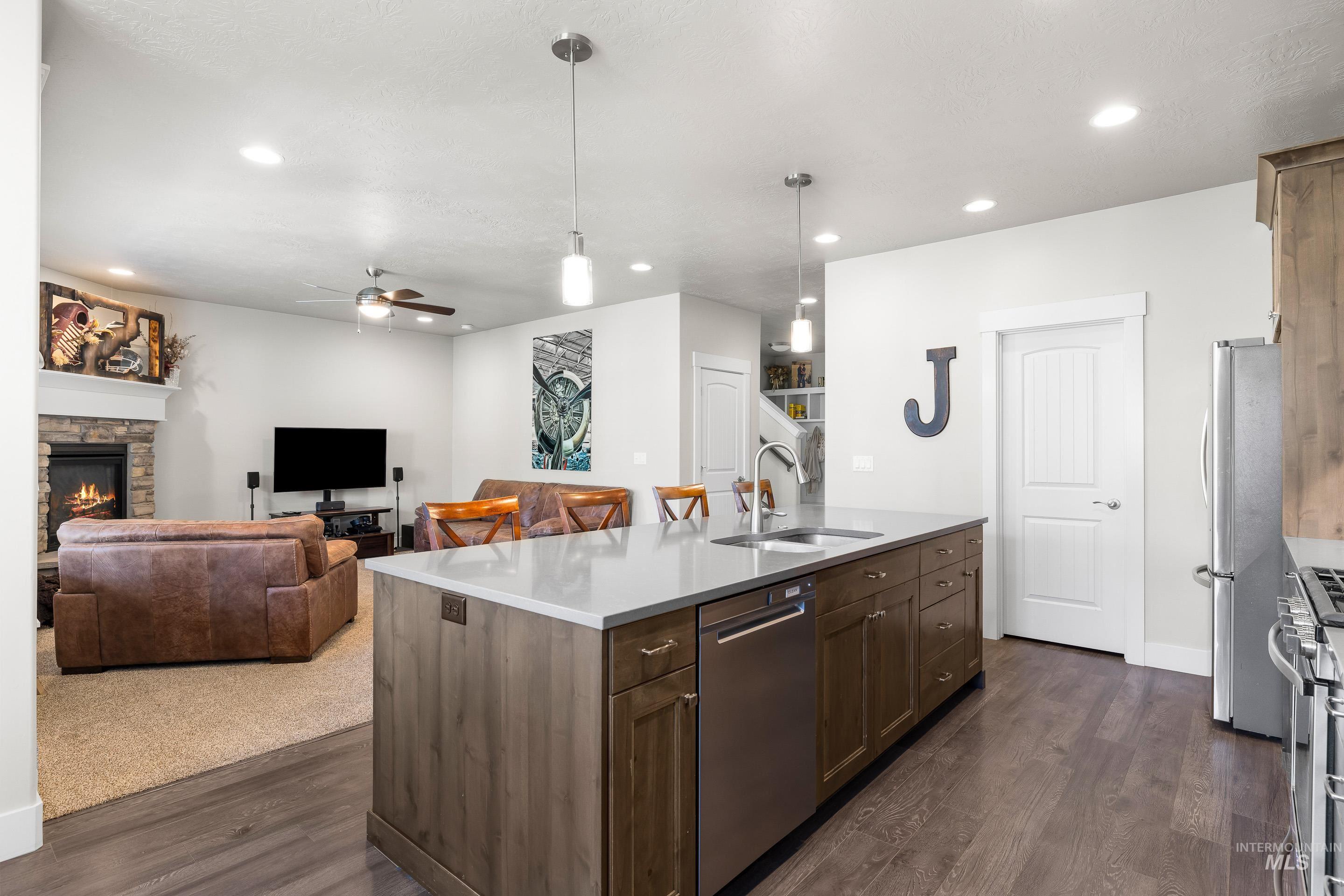 Kitchen with pendant lighting, a fireplace, a ceiling fan, dark wood finished floors, and recessed lighting